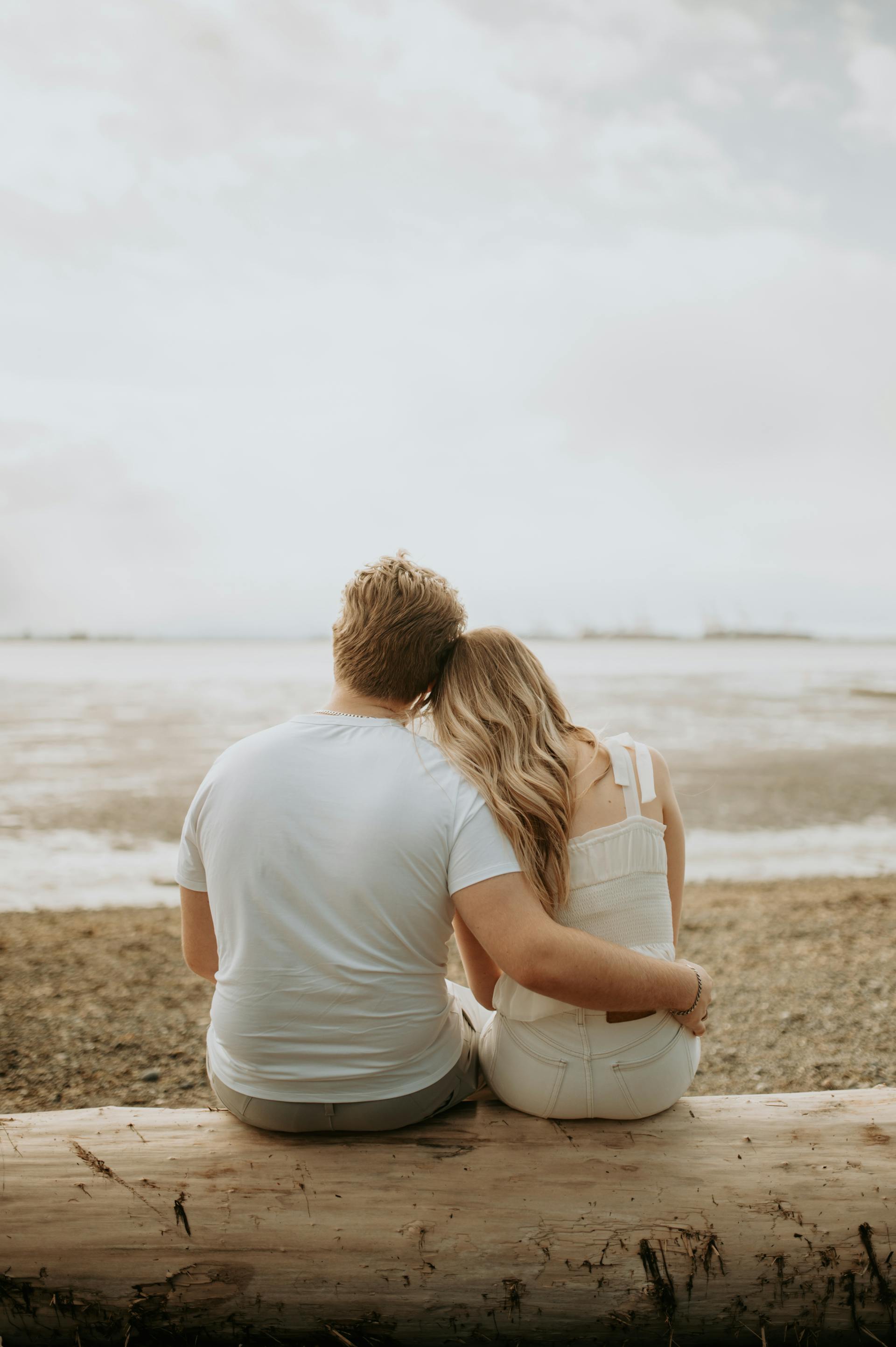 Rückansicht eines Paares, das am Strand sitzt | Quelle: Pexels