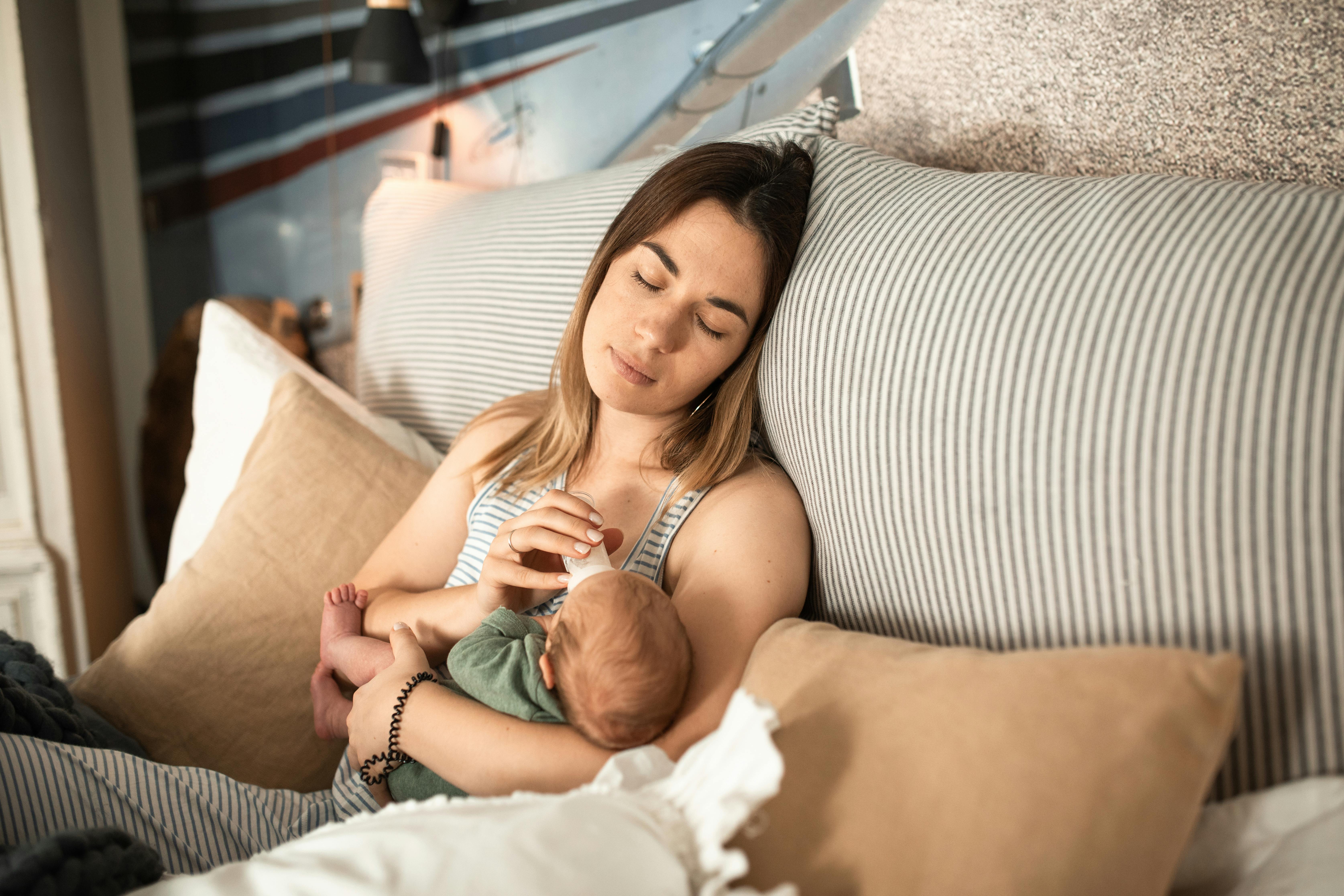 Eine erschöpfte Frau, die ein neugeborenes Baby füttert | Quelle: Pexels