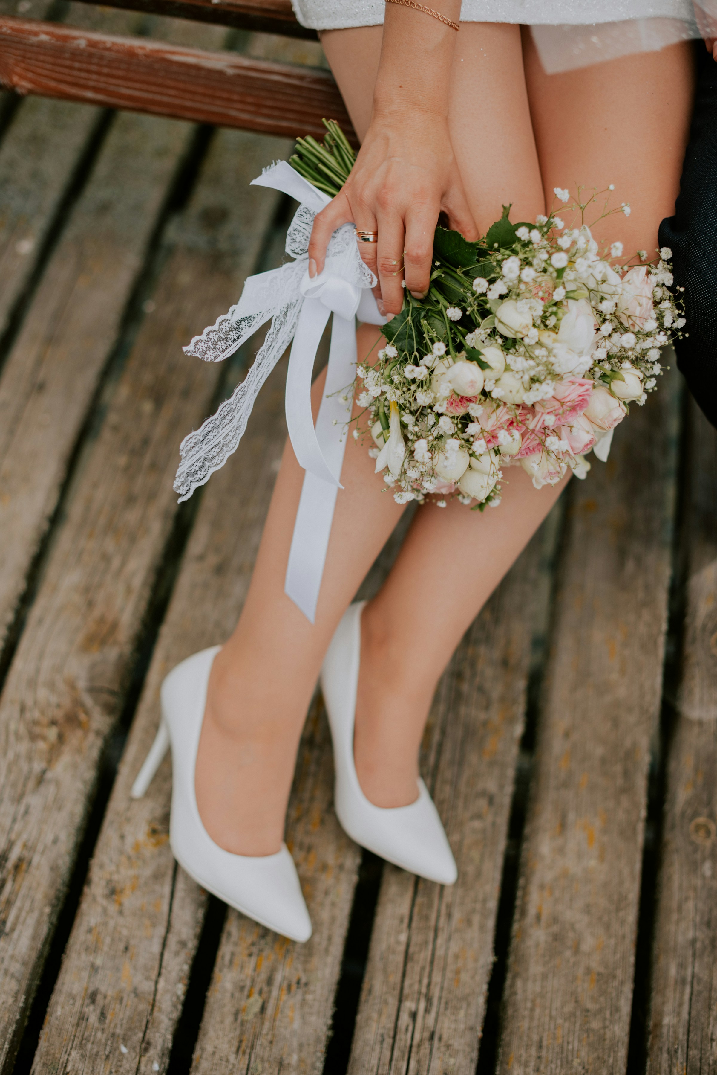 Eine Braut in weißen Absätzen, die Blumen hält | Quelle: Unsplash