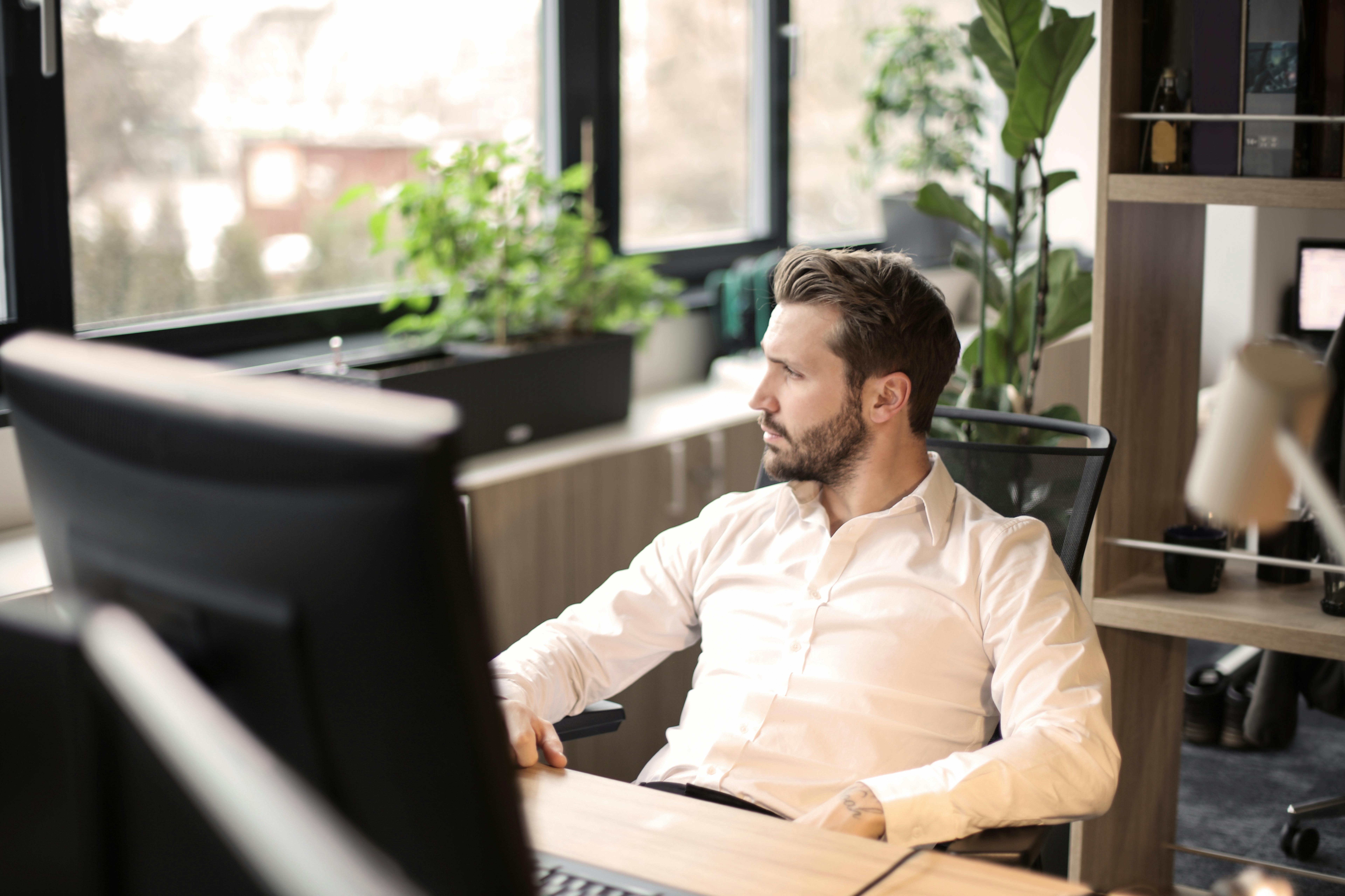 Ein Mann schaut aus dem Fenster, während er auf einem Stuhl sitzt | Quelle: Pexels