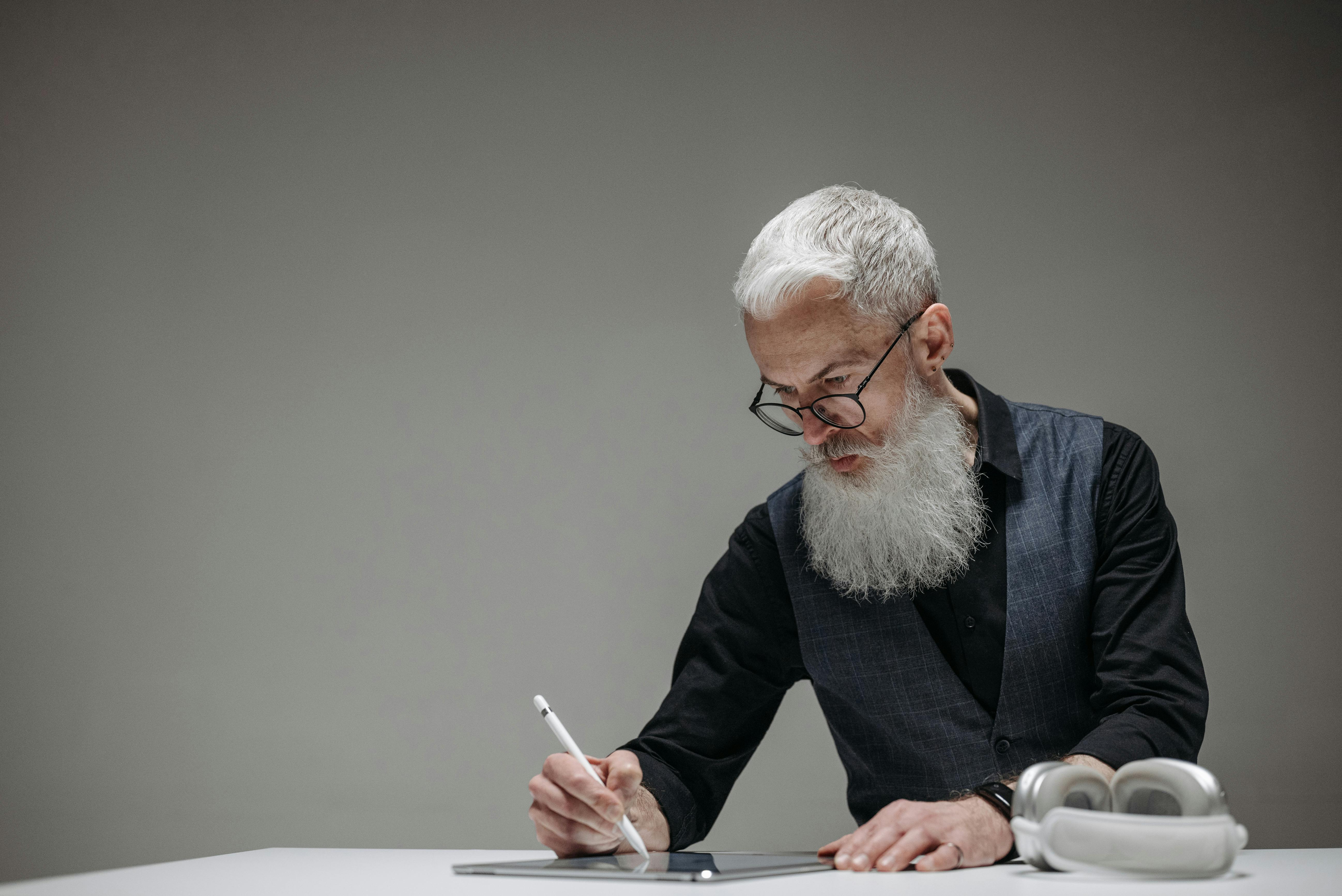 Bärtiger Mann, der einen Lichtstift auf einem Tablet benutzt | Quelle: Pexels