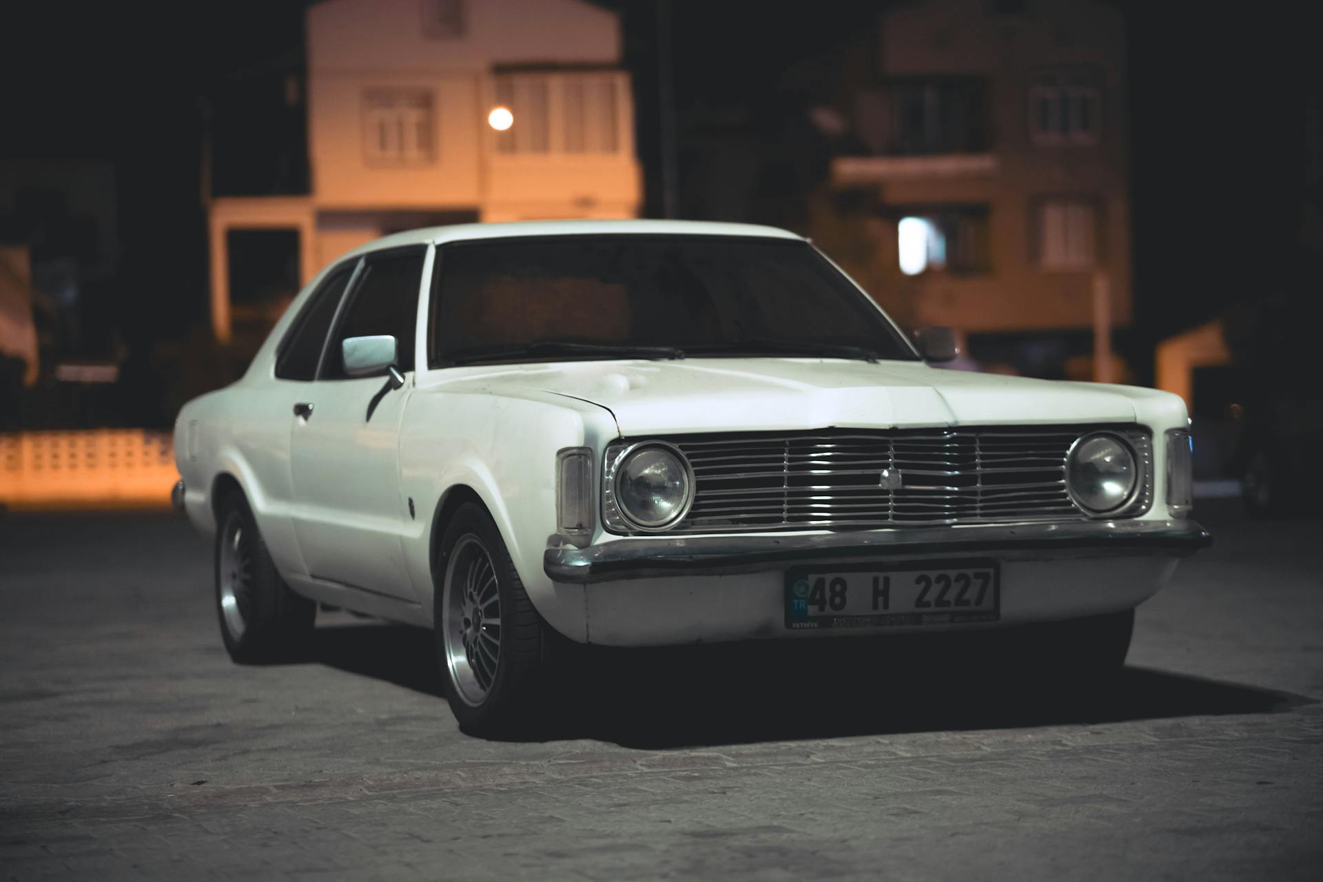 Ein weißer Oldtimer, der nachts auf einer Straße geparkt ist | Quelle: Pexels