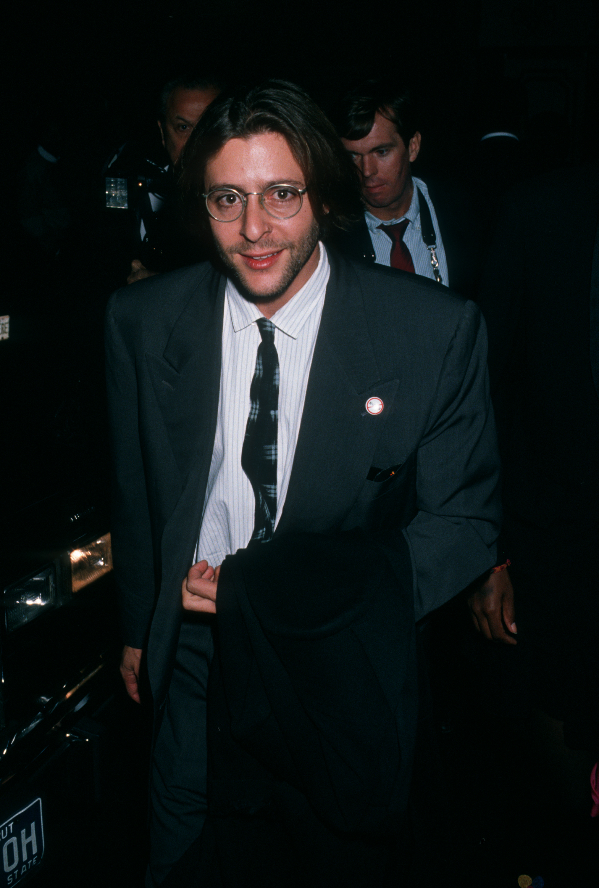Mit einer Brille mit rundem Rahmen und in einem dunklen Anzug kommt der Schauspieler im Ziegfeld Theater in New York City zur Premiere von