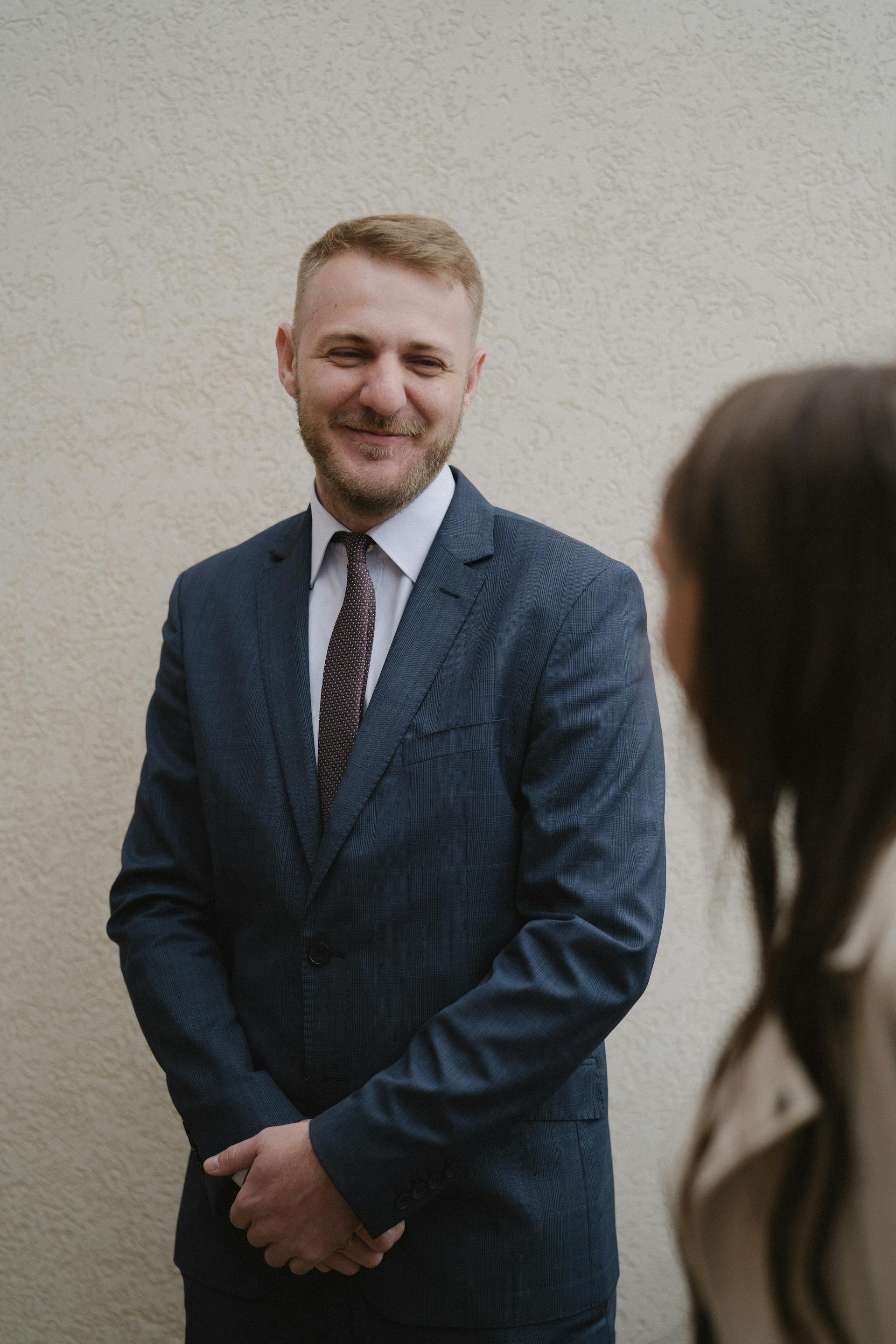 Ein Mann in einem schicken Anzug grinst eine Frau an | Quelle: Pexels