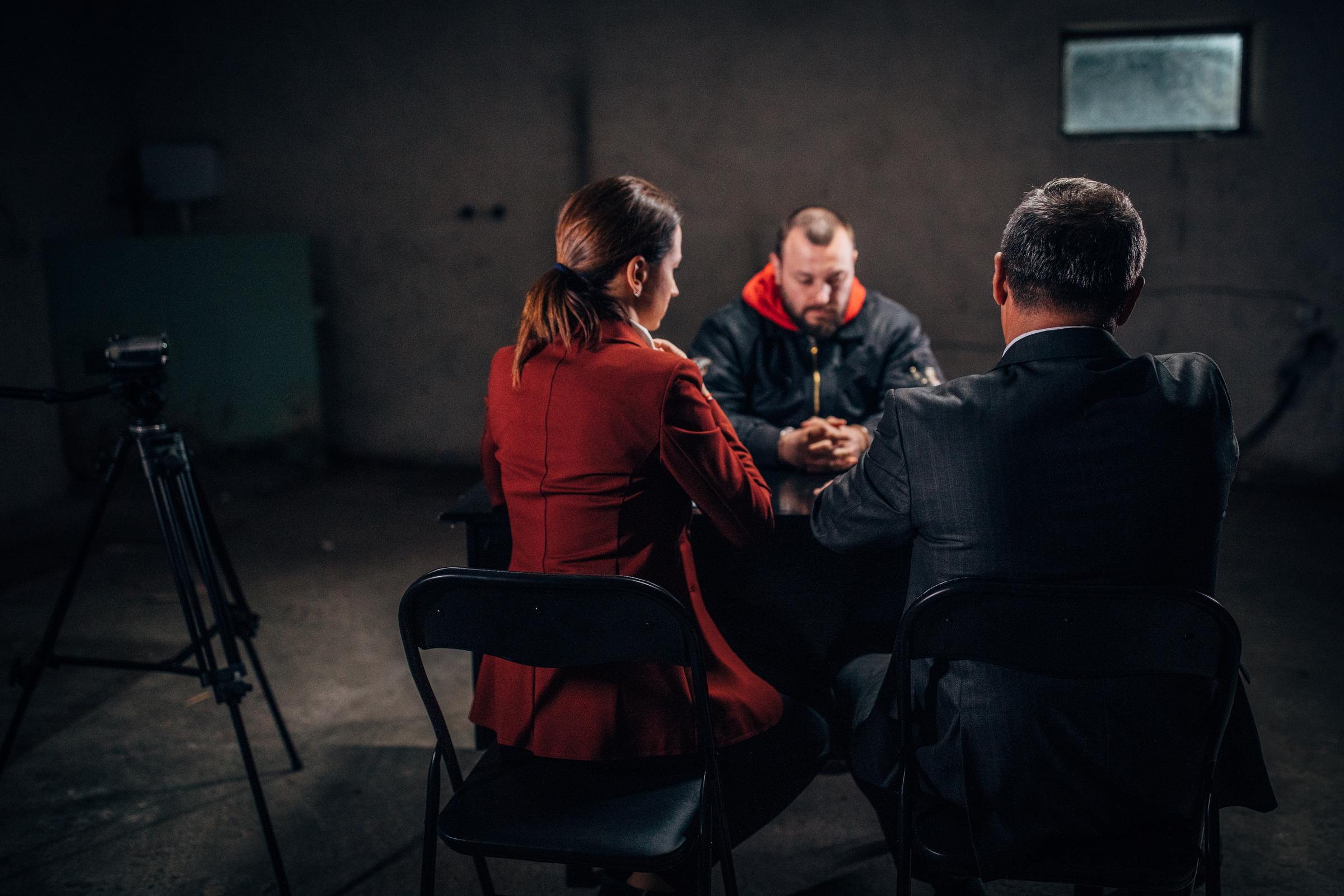 Mann mit Handschellen und zwei Detektiven | Quelle: Getty Images