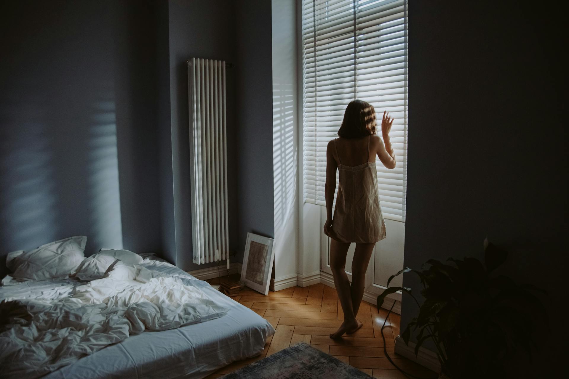Eine Frau steht neben den Fensterläden ihres Schlafzimmers | Quelle: Pexels