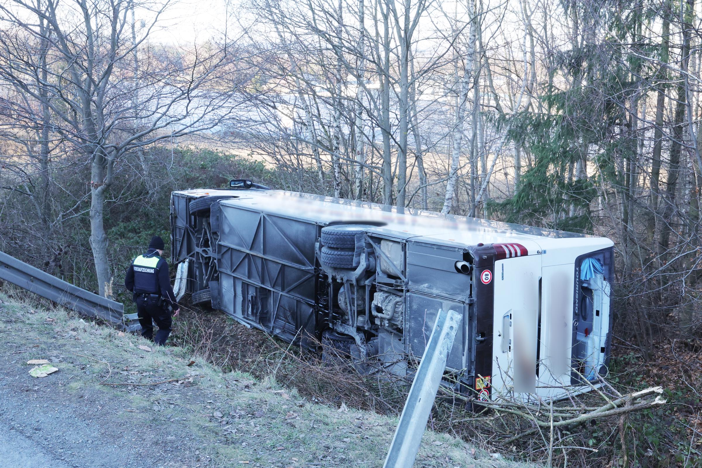 19. Januar 2026, Thüringen, Schleiz: Ein Polizeibeamter begibt sich zum Ort eines Busunglücks mit mehreren Verletzten. Der Reisebus war auf die Seite gekippt und einen Abhang hinuntergerutscht. | Quelle: Getty Images