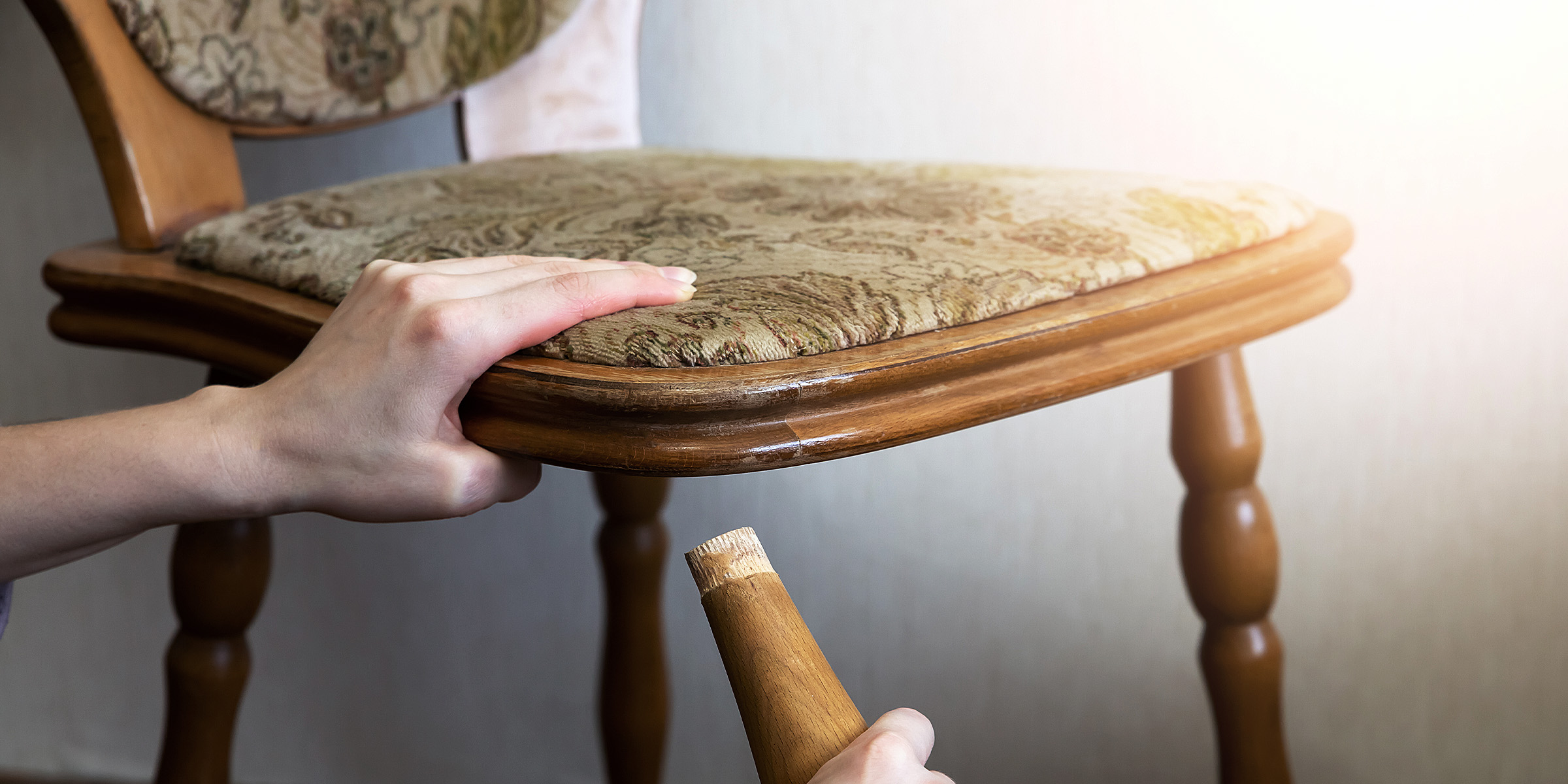 Eine Frau, die das Bein eines gebrochenen Stuhls hält | Quelle: Shutterstock