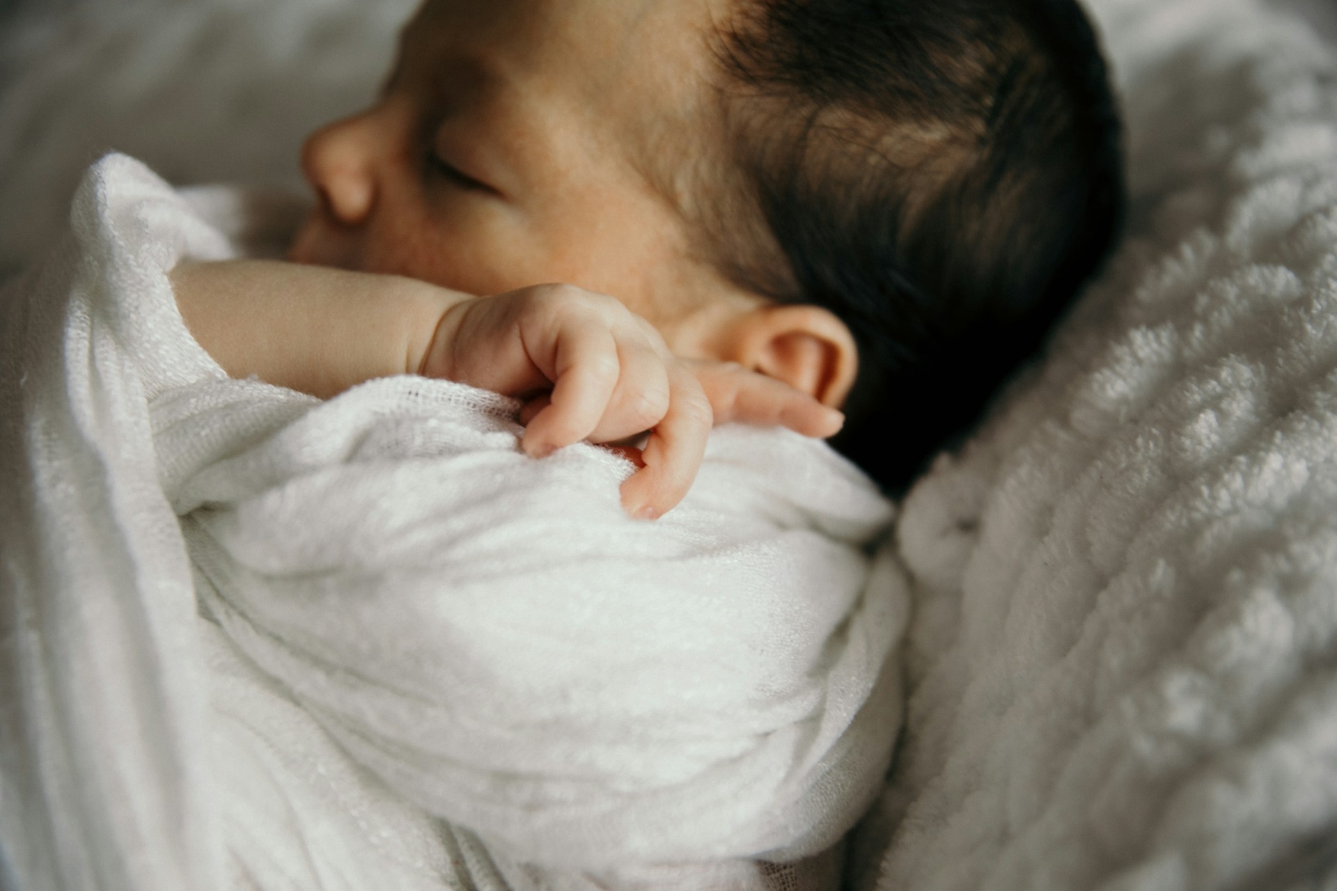 Ein neugeborenes Baby, eingewickelt in eine Decke | Quelle: Unsplash