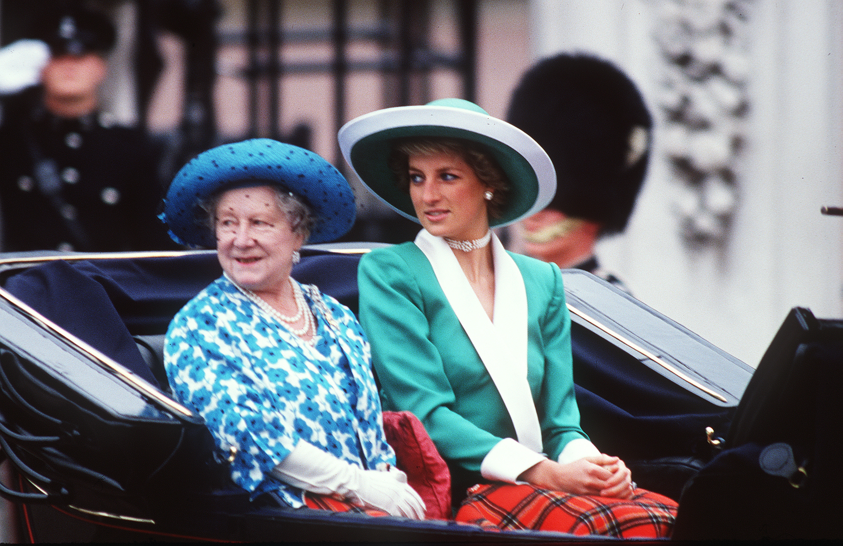 Diana, Prinzessin von Wales, reitet neben der Königinmutter in der Kutsche während des Trooping the Colour 1988 in London. Gekleidet in ein anmutiges grünes Kleid mit einem weißen Kragen und einem dazu passenden Philip Somerville-Hut, bietet Diana ein Bild von klassischer königlicher Eleganz inmitten der feierlichen Pracht.