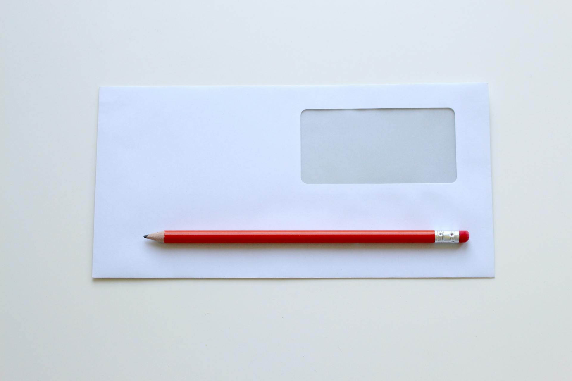 Roter Bleistift auf einem weißen Umschlag liegend | Quelle: Pexels