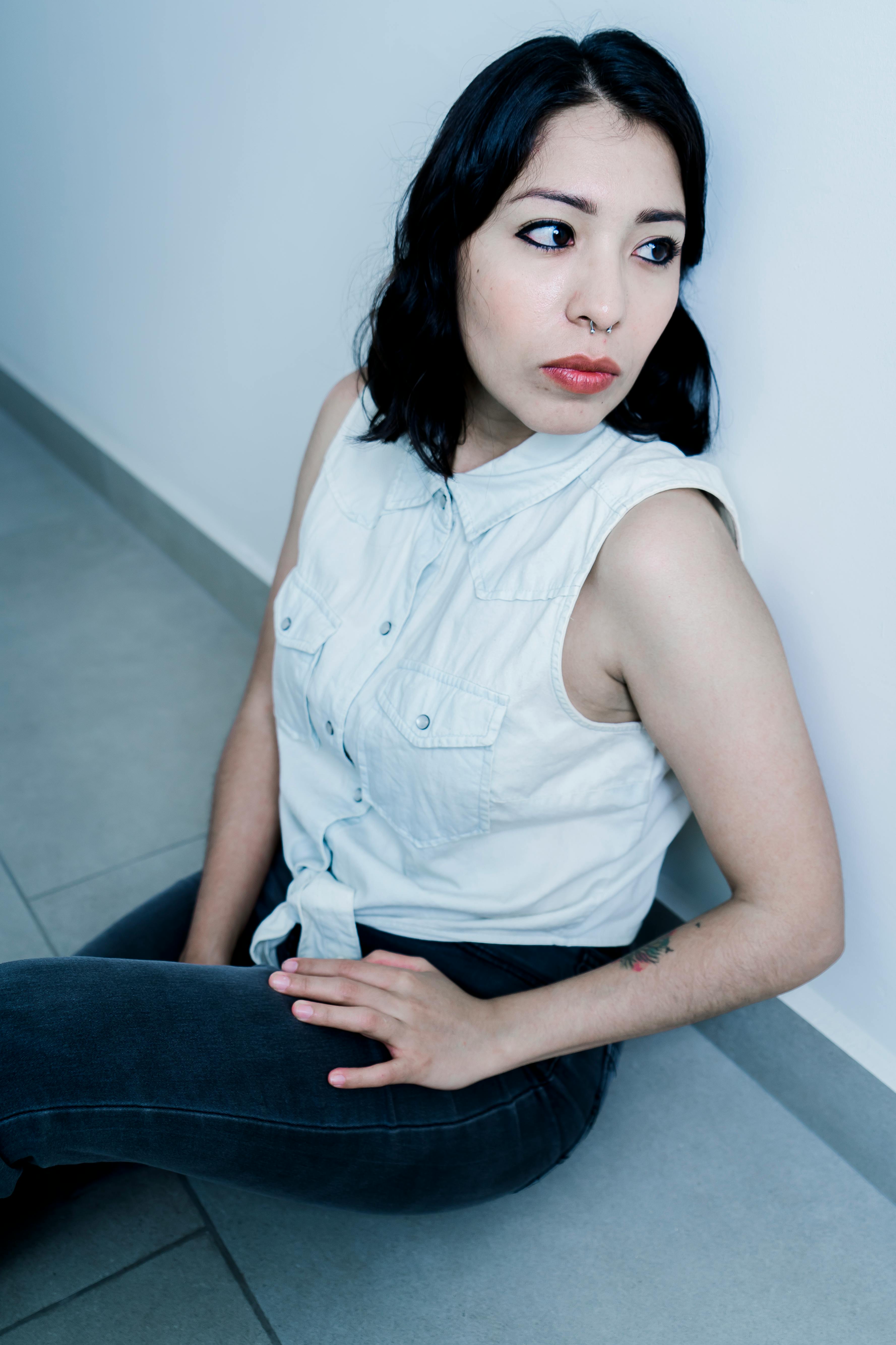 Eine ernste Frau, die zur Seite schaut, während sie auf dem Boden sitzt | Quelle: Pexels