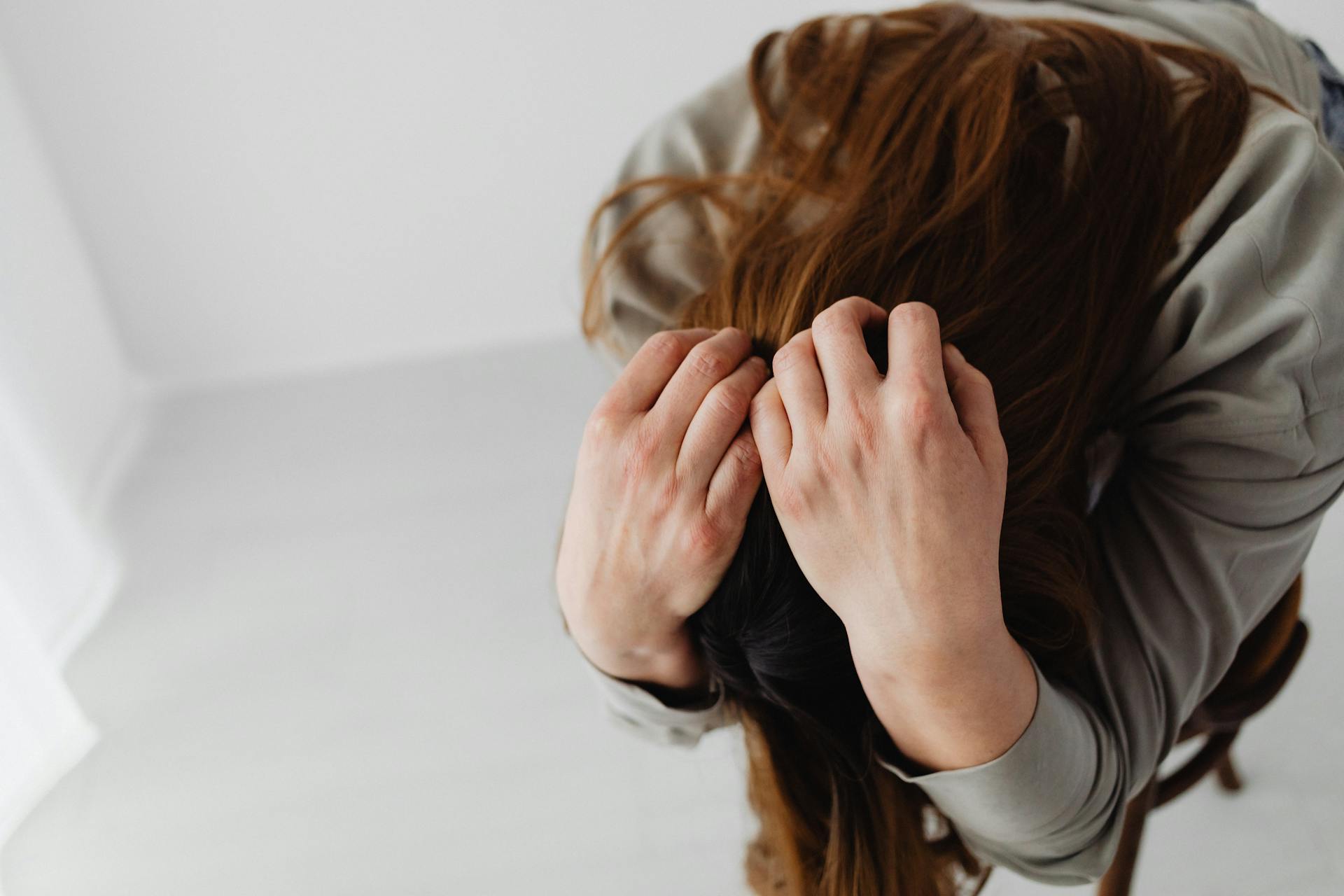 Eine Frau sitzt mit dem Kopf in den Händen | Quelle: Pexels