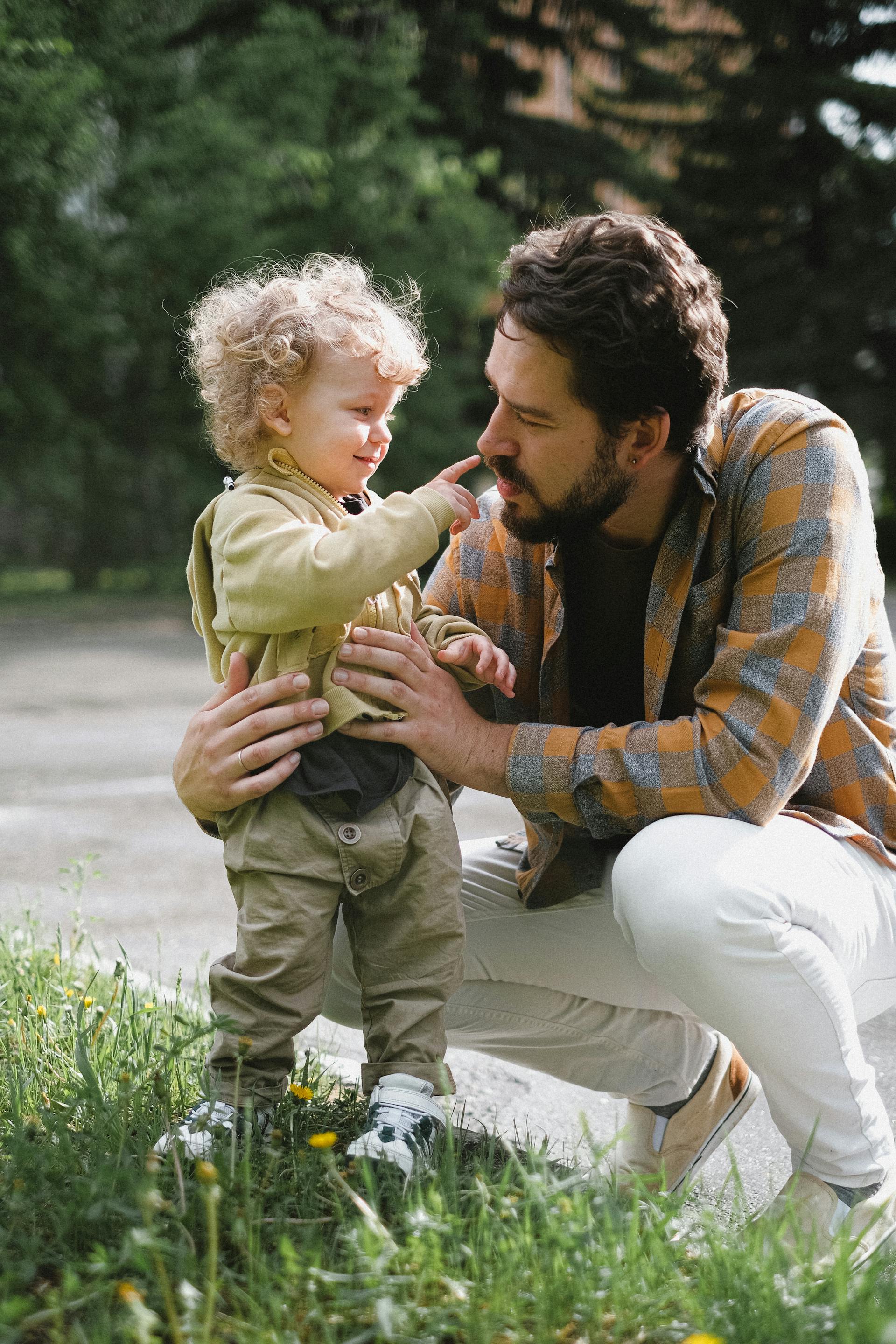 Ein Vater und sein Sohn teilen einen süßen Moment im Freien | Quelle: Pexels