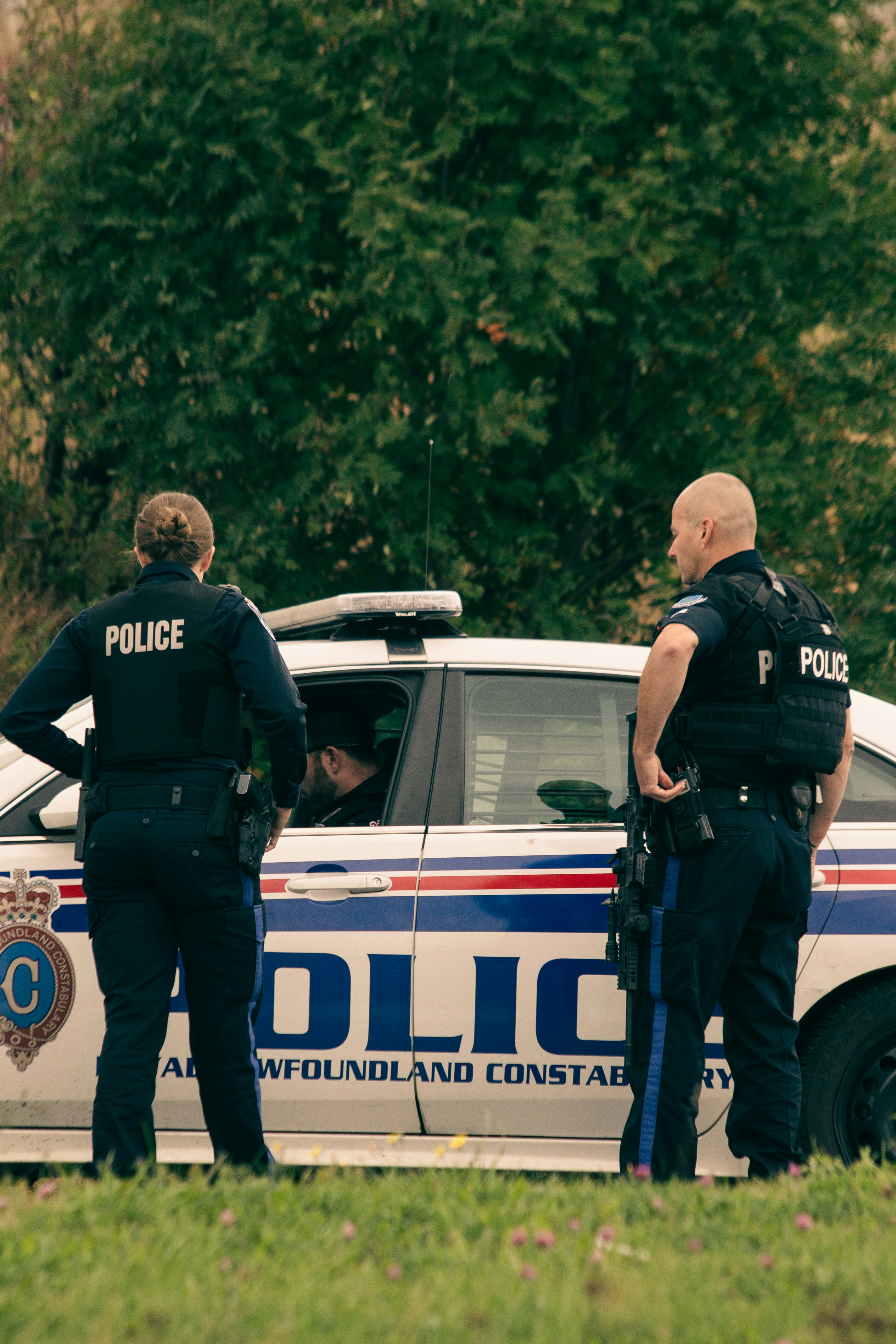 Polizeibeamte stehen vor einem Polizeiauto | Quelle: Unsplash