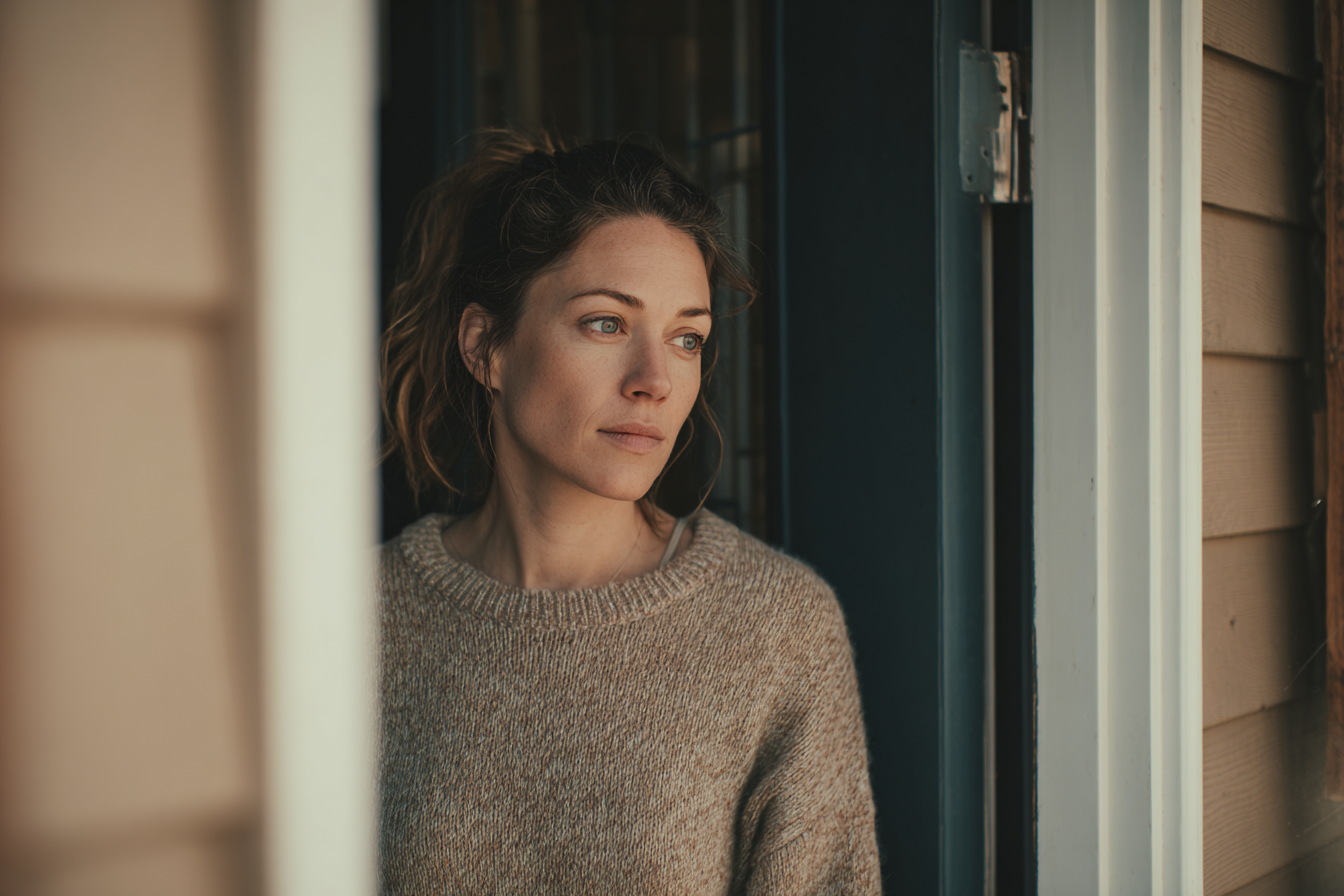 Eine Frau, die in der Tür ihres Hauses steht | Quelle: Midjourney