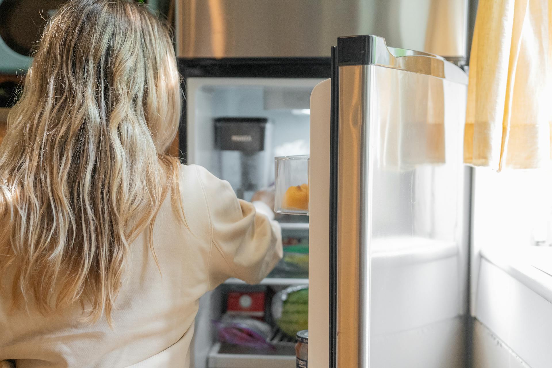 Eine Frau greift in einen Kühlschrank | Quelle: Pexels