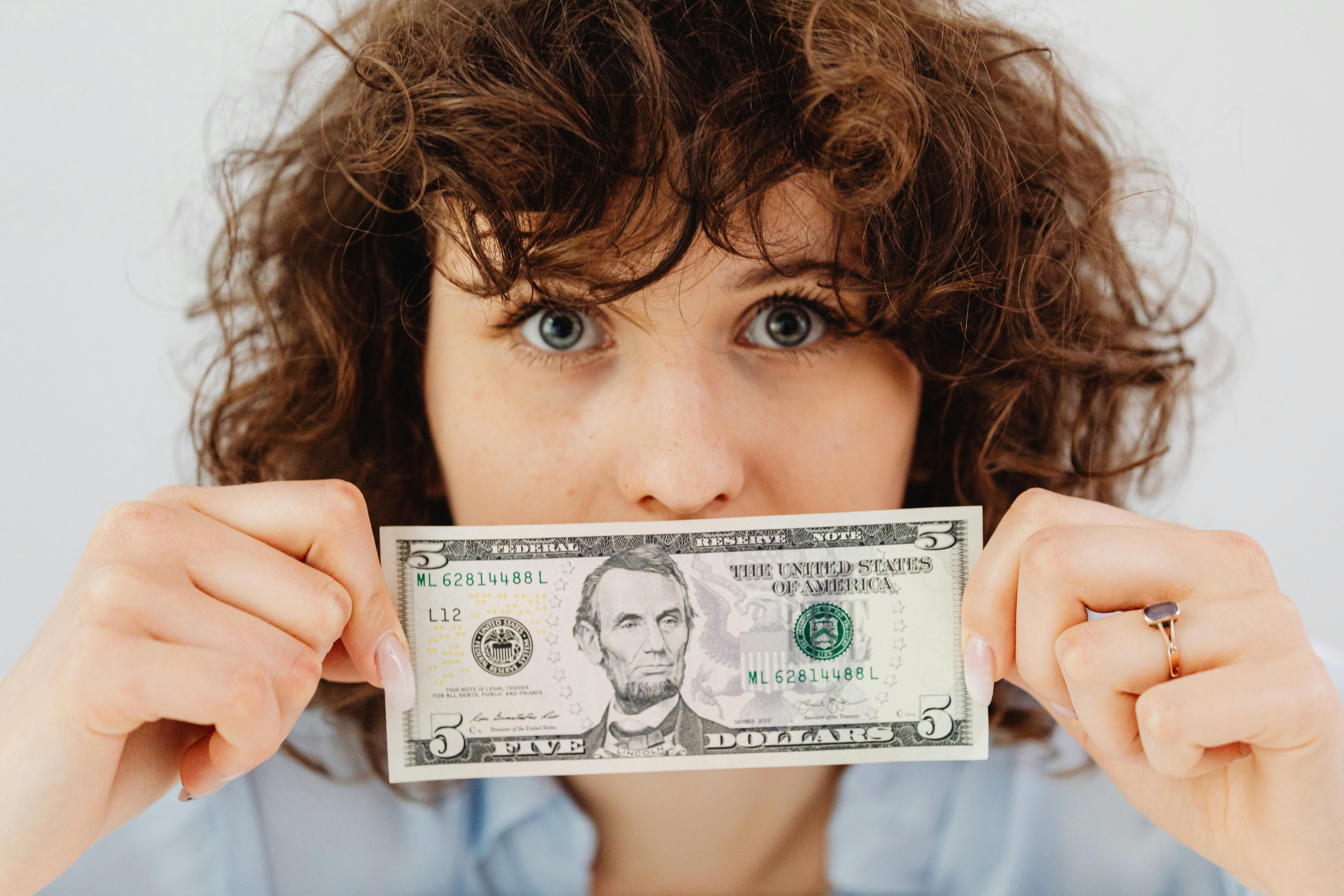 Eine Person hält einen Dollarschein | Quelle: Pexels