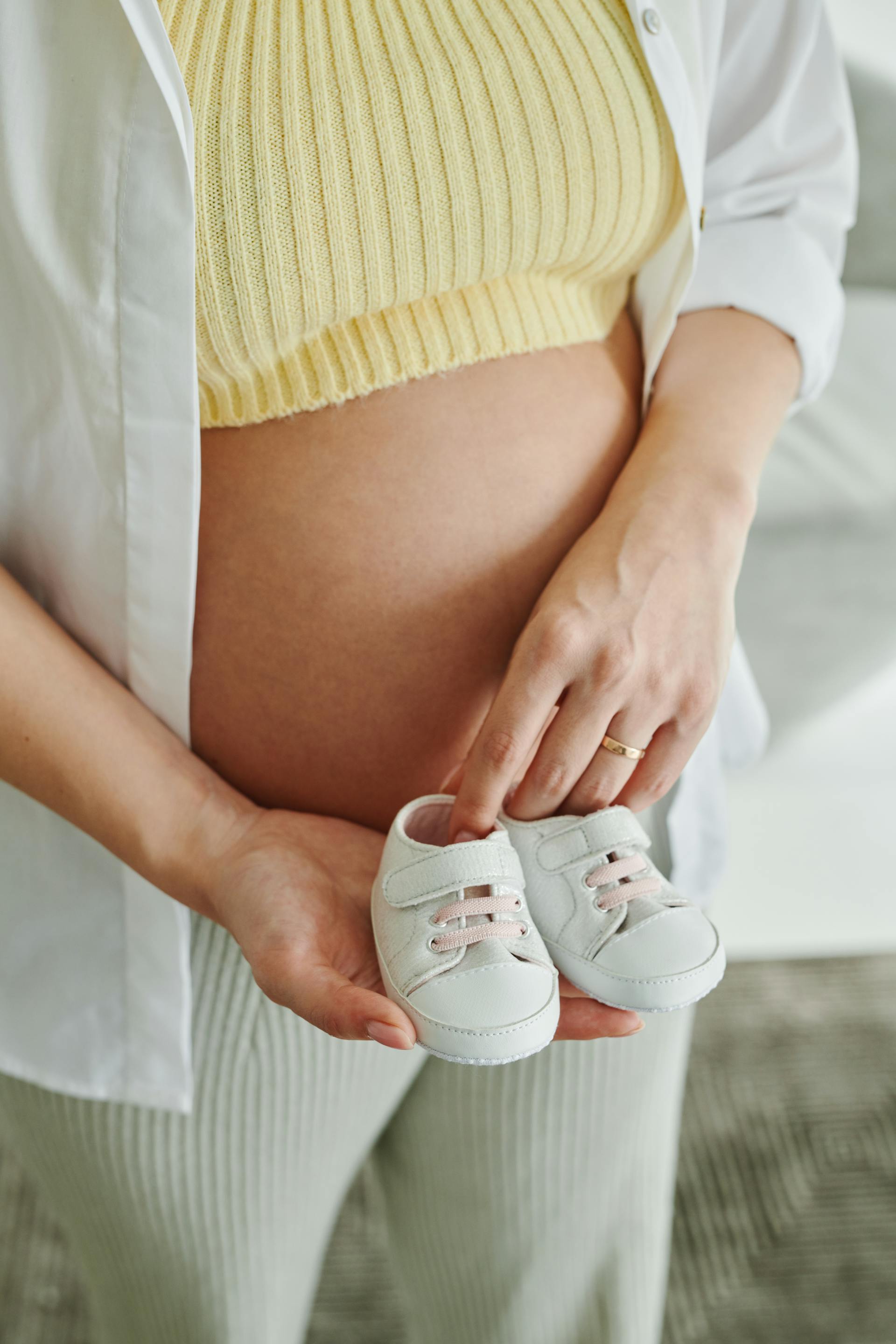 Eine schwangere Frau mit Babyschuhen | Quelle: Pexels
