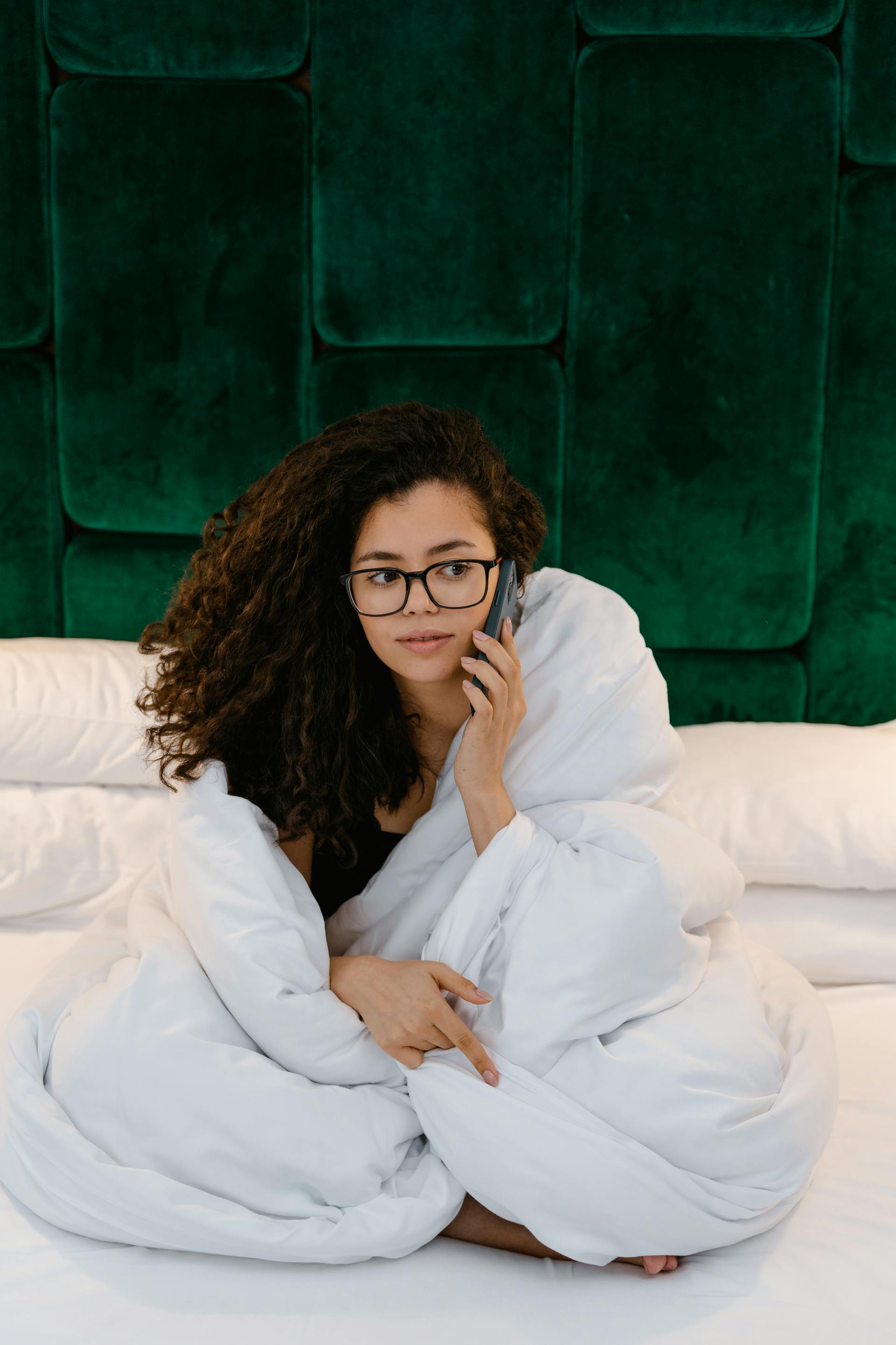 Eine Frau, die im Bett mit ihrem Telefon spricht | Quelle: Pexels