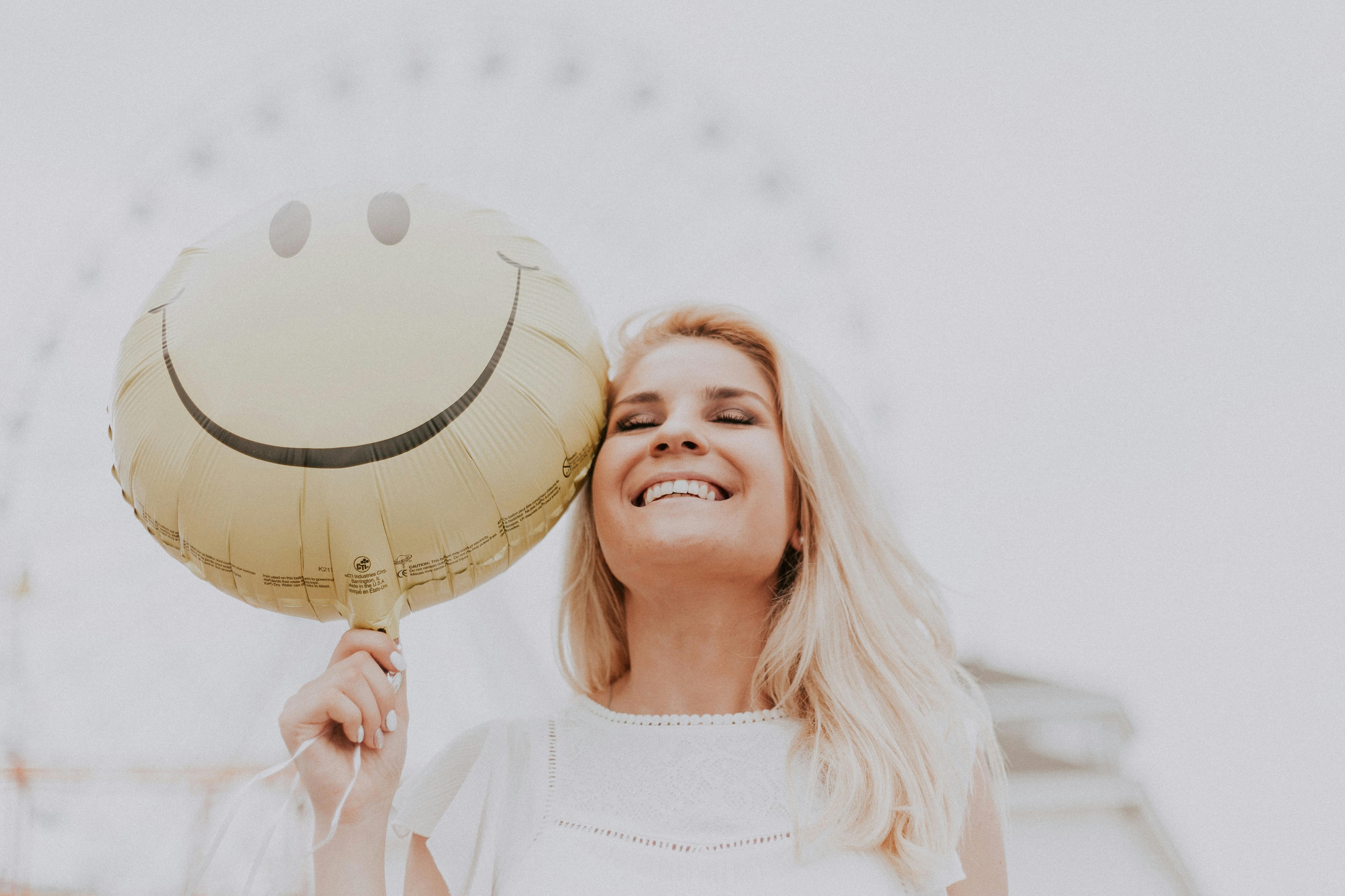 Eine lächelnde Frau, die einen Luftballon hält | Quelle: Pexels