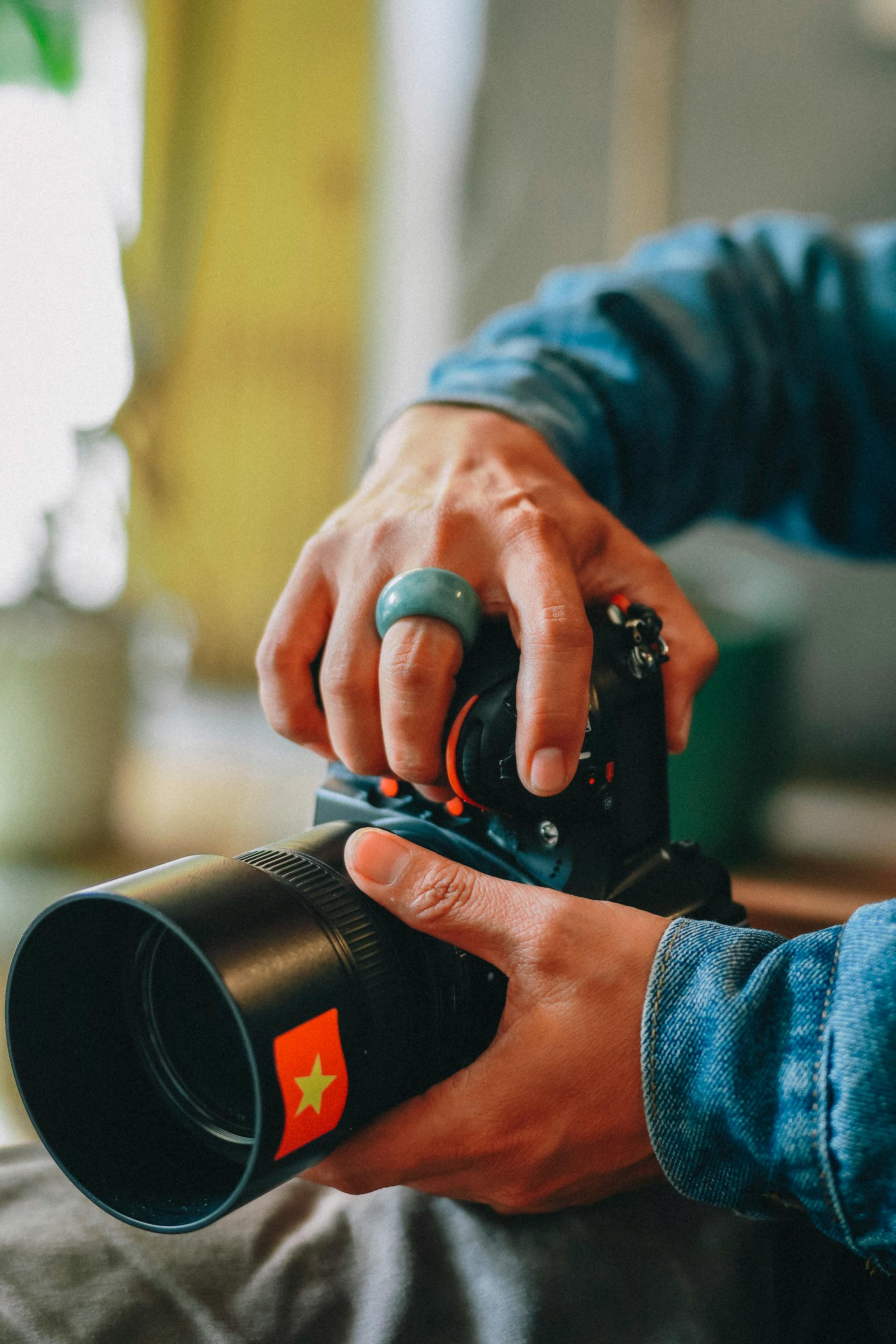 Eine Nahaufnahme eines Fotografen, der sein Kameraobjektiv einstellt | Quelle: Pexels