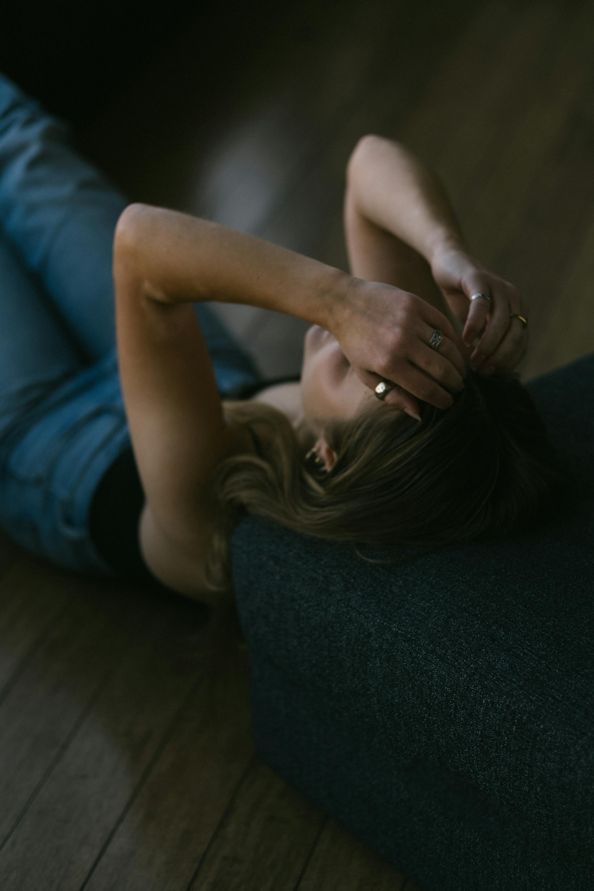 Eine Frau, die auf dem Boden liegt und die Hände auf dem Kopf hat | Quelle: Pexels