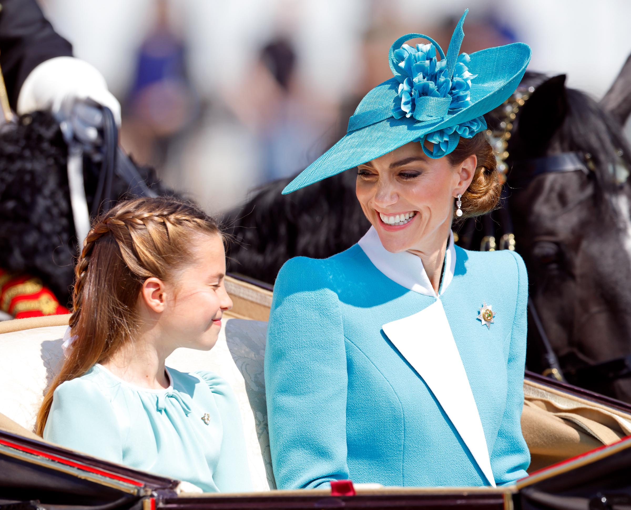 Prinzessin Charlotte von Wales und Catherine, Prinzessin von Wales, lächeln sich an, als sie den Buckingham Palast während der Trooping The Colour Parade 2025 in einer Pferdekutsche verlassen.