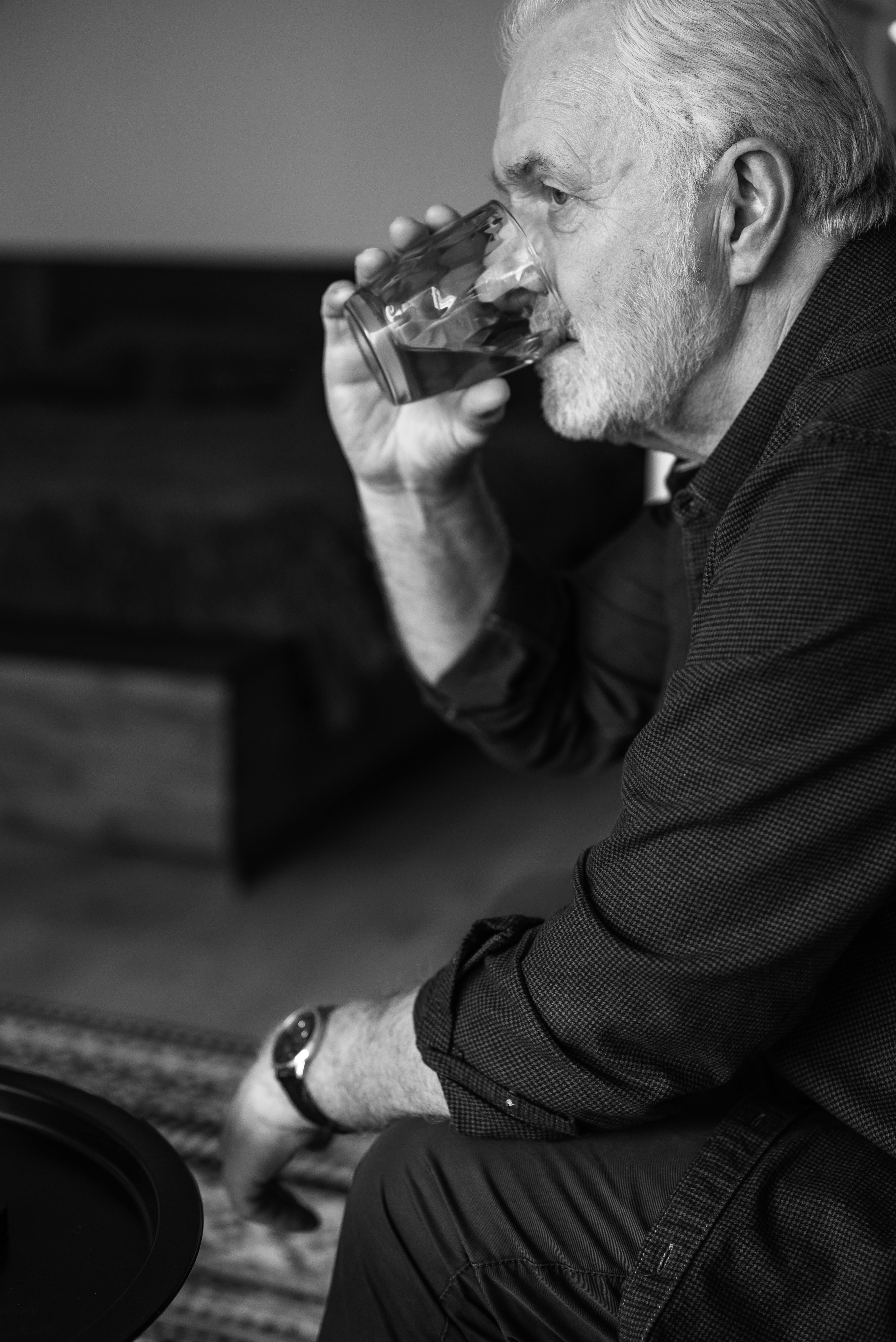 Mann sitzt auf einer Couch und trinkt Wasser | Quelle: Pexels