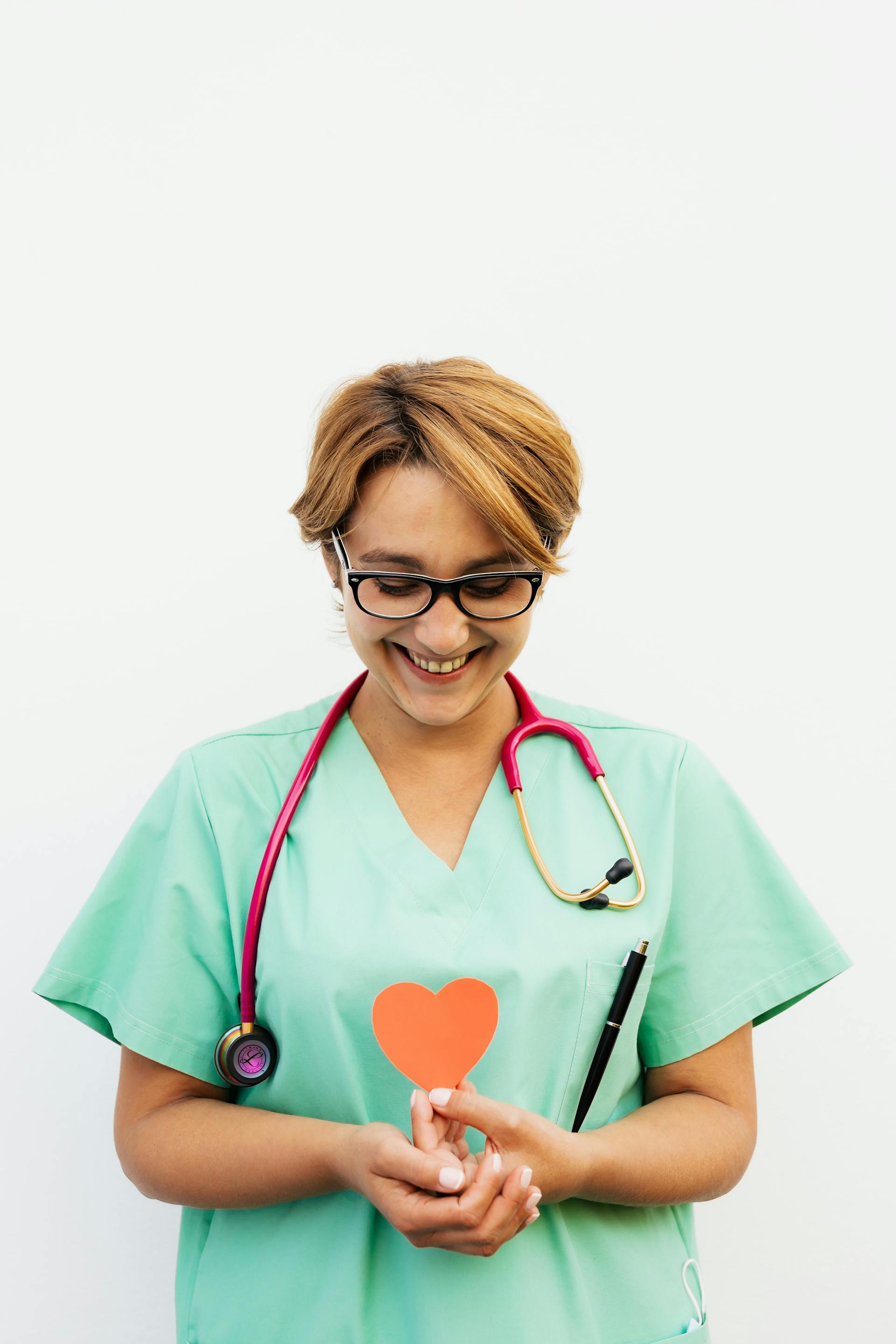 Eine lächelnde Krankenschwester, die ein rotes Papierherz hält | Quelle: Pexels