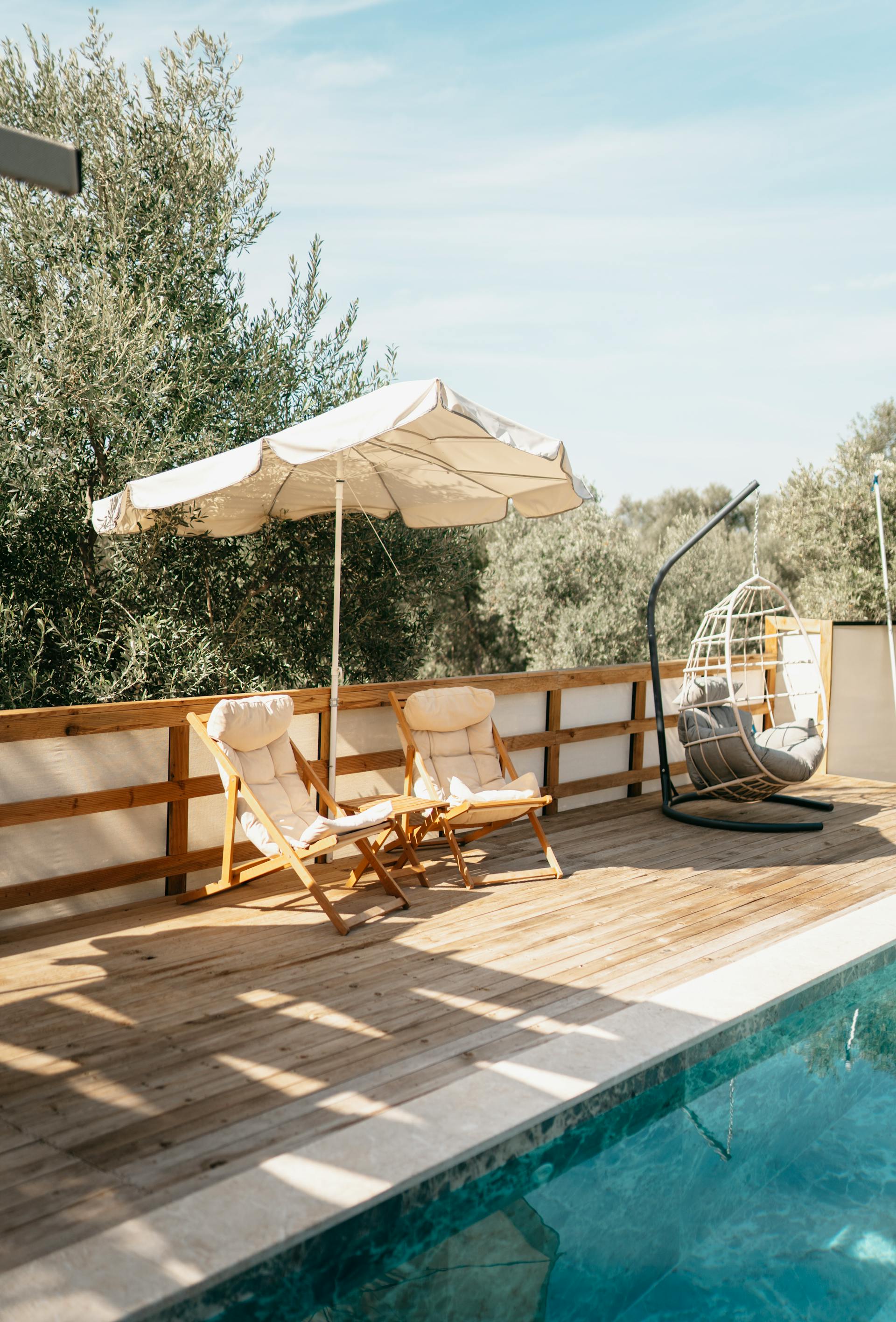 Ein Sonnenschirm und Liegestühle in der Nähe eines Pools | Quelle: Pexels