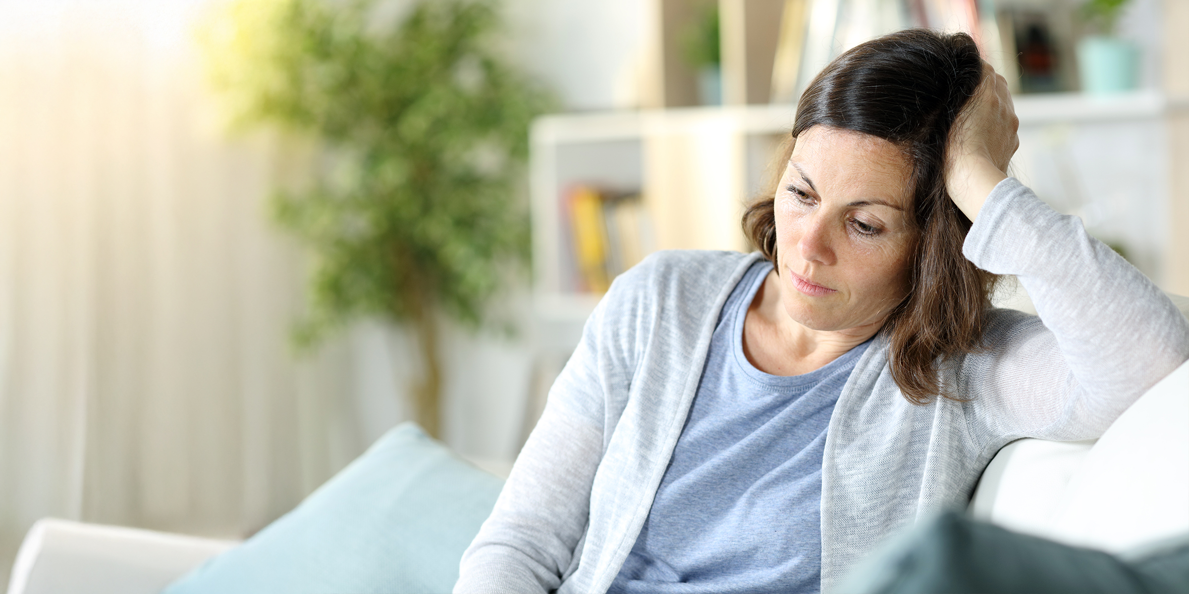 Eine traurige und nachdenkliche Frau in einem Wohnzimmer | Quelle: Shutterstock