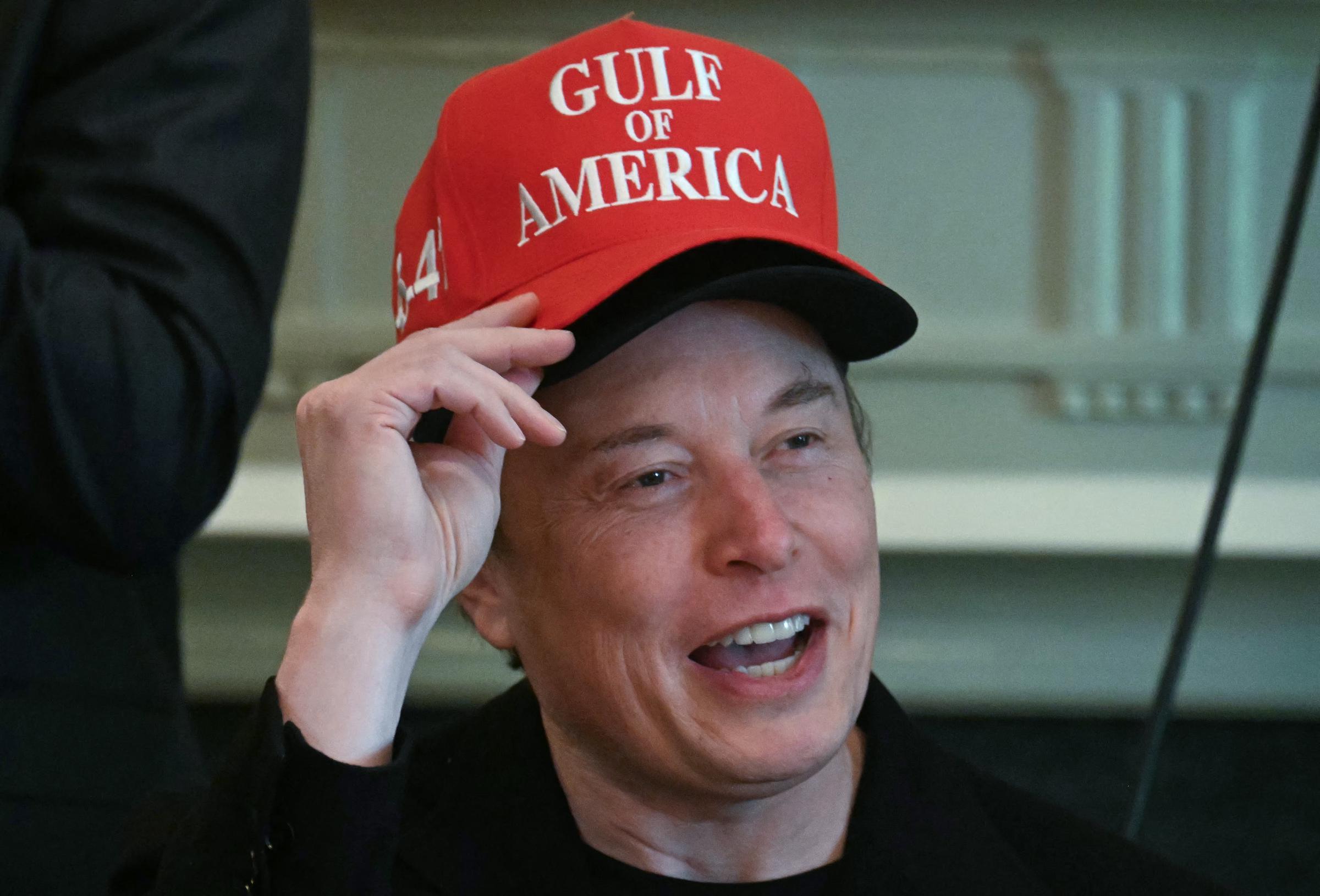 Elon Musk trägt zwei Hüte, während er während einer Kabinettssitzung spricht | Quelle: Getty Images