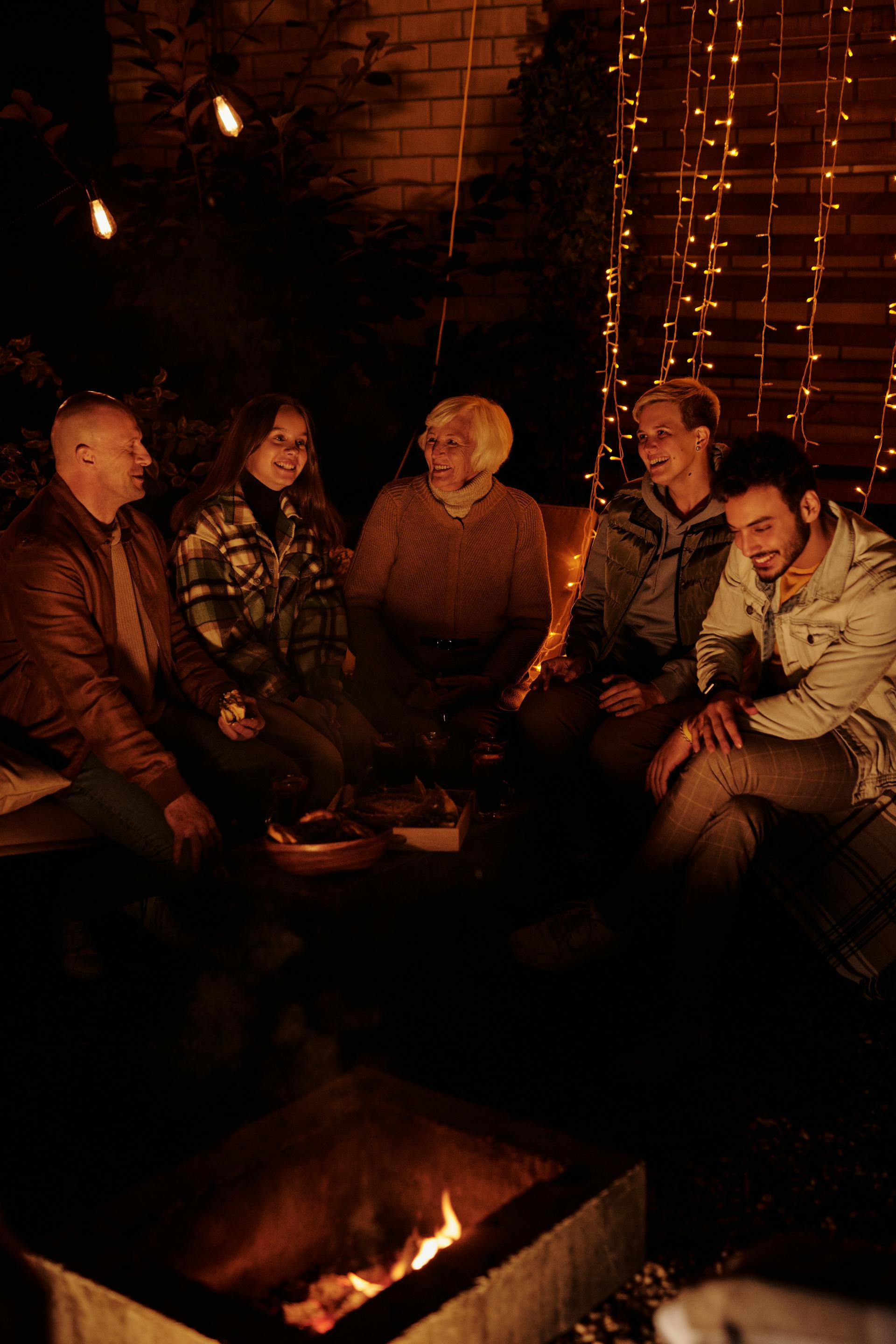 Eine Familie versammelt sich nachts um ein Lagerfeuer | Quelle: Pexels