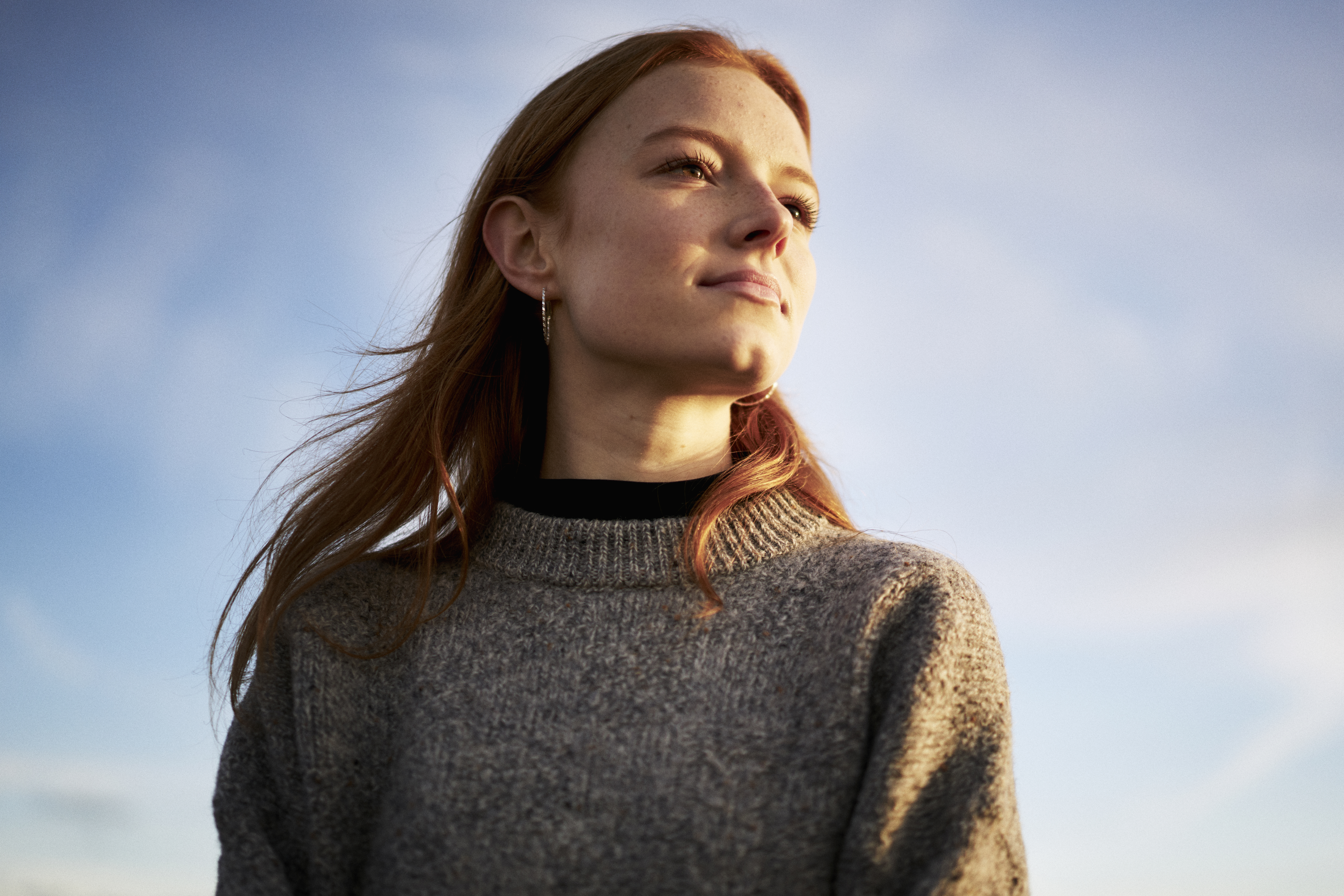Junge Frau, die zufrieden in der Wintersonne sitzt | Quelle: Getty Images