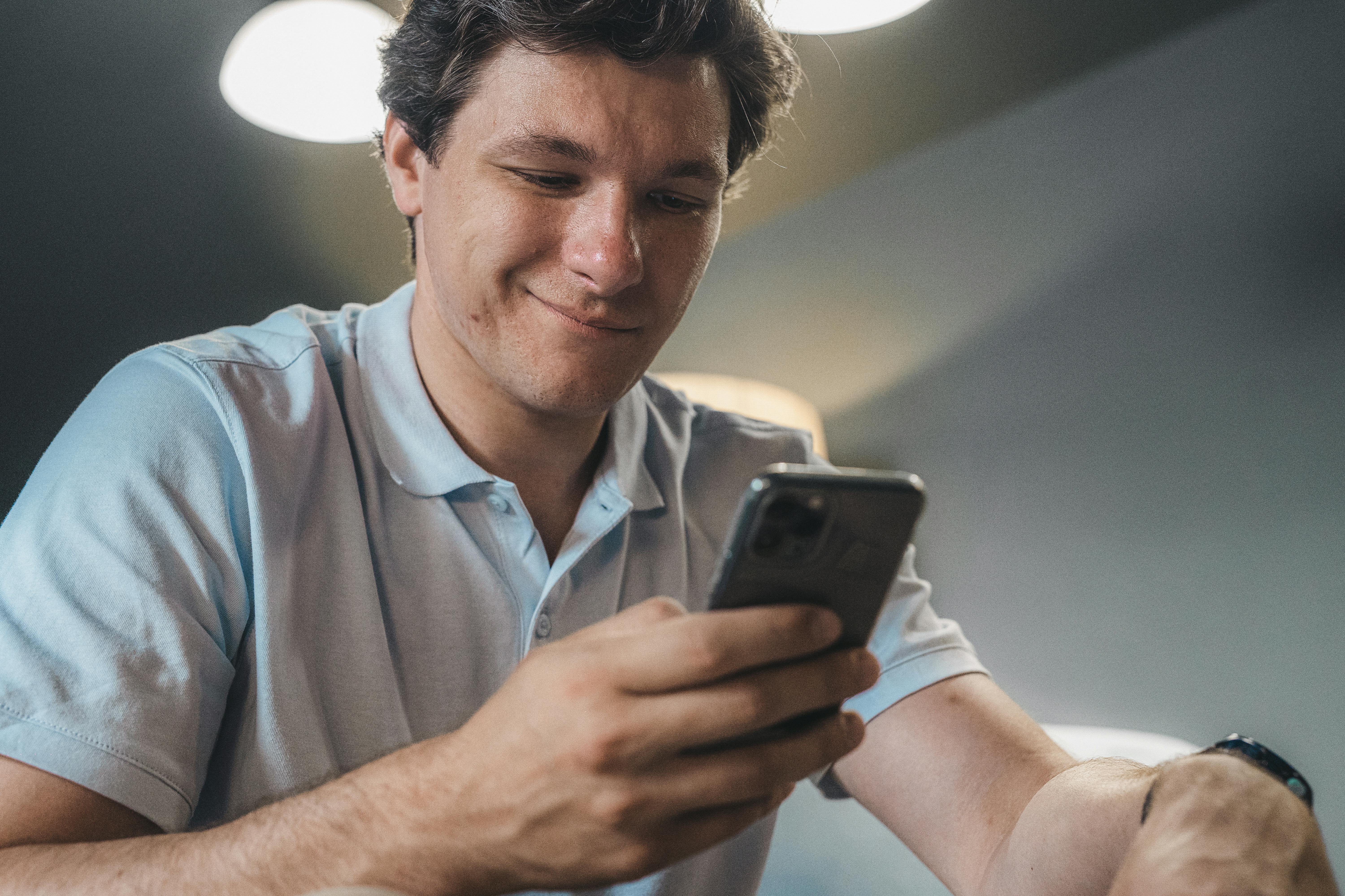 Ein glücklicher Mann, der sein Handy benutzt | Quelle: Pexels