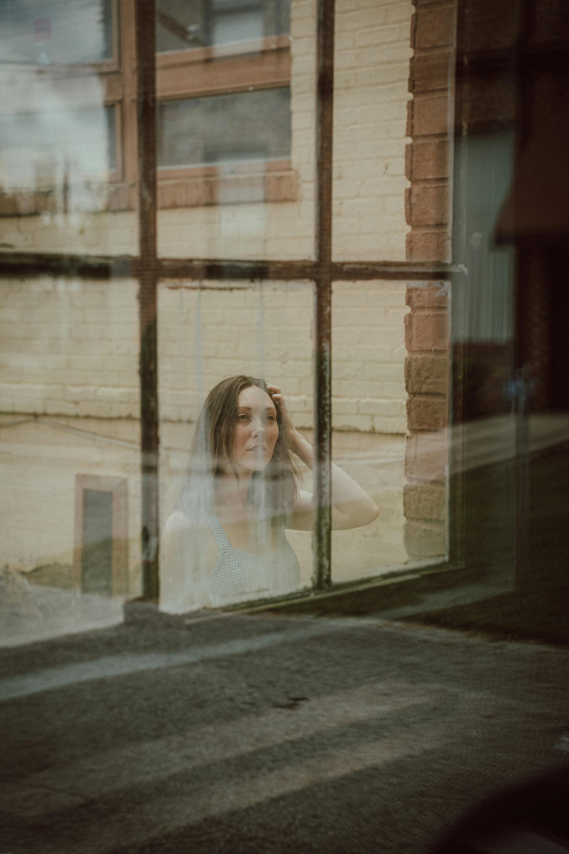 Eine Frau schaut durch das Fenster eines Gebäudes | Quelle: Pexels