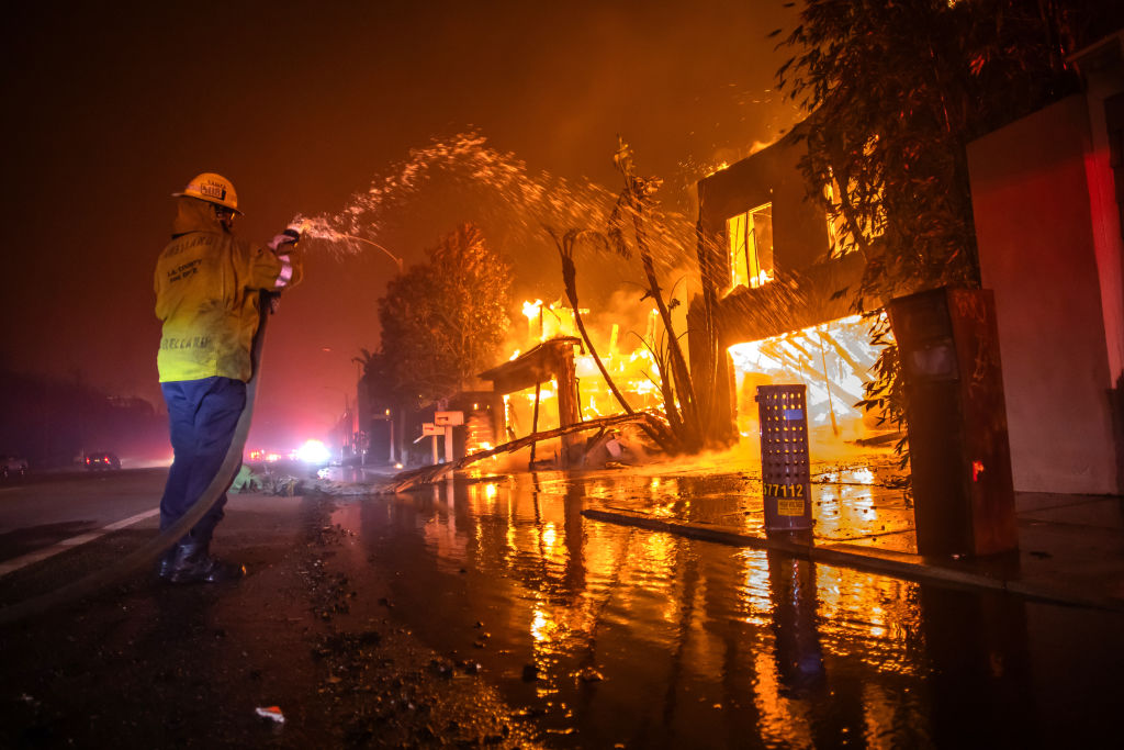 Ein Feuerwehrmann bekämpft den Palisades-Brand, während dieser am 8. Januar 2025 in Los Angeles, Kalifornien, inmitten eines starken Sturms Häuser an der Pacific Coast Highway zerstört. | Quelle: Getty Images