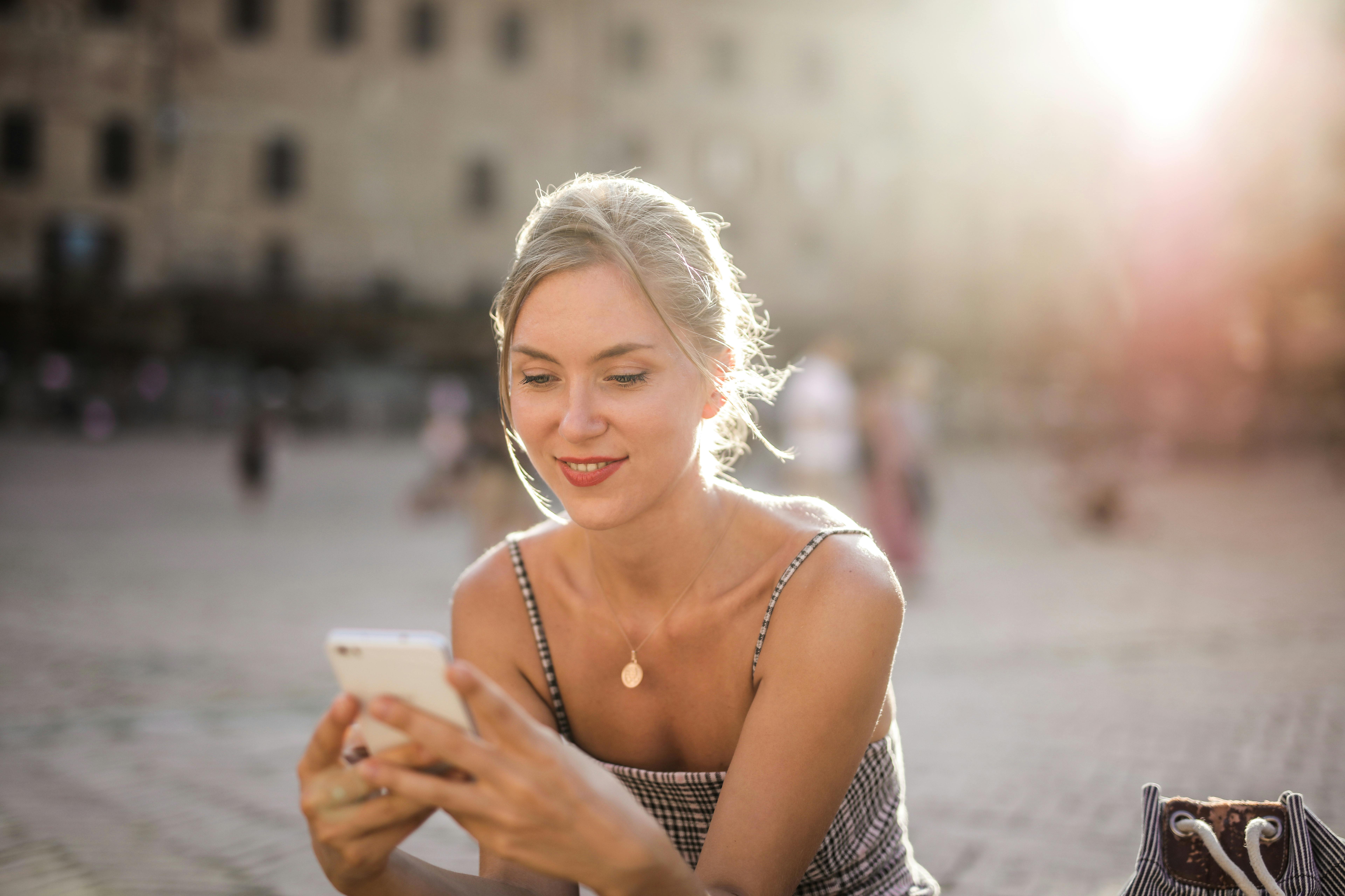 Eine glückliche Frau, die ihr Telefon benutzt | Quelle: Pexels
