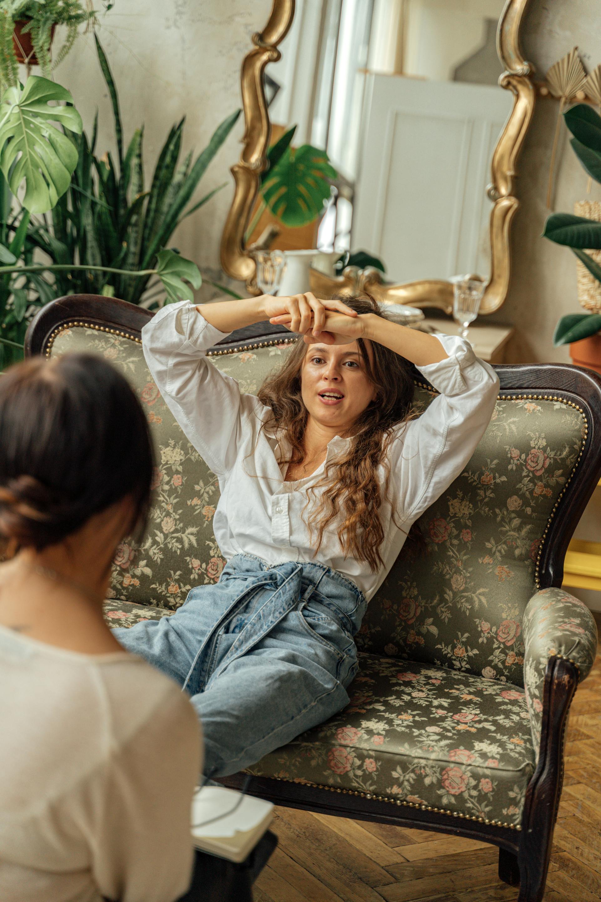 Eine Frau sitzt auf einem Sofa und spricht mit ihrer Freundin | Quelle: Pexels