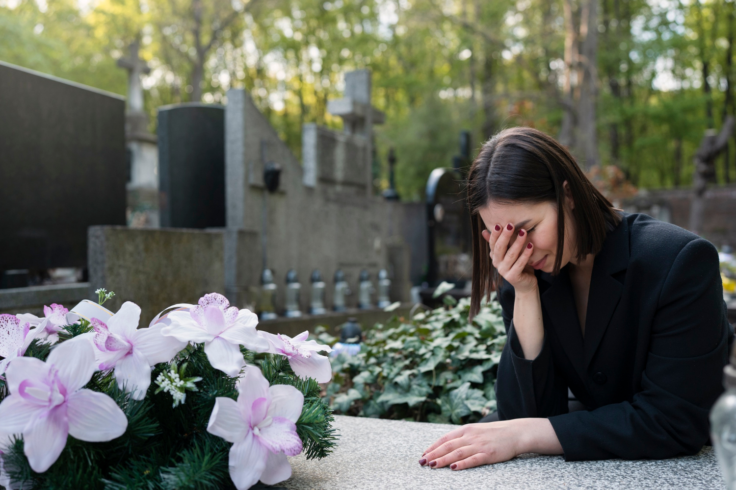 Eine trauernde Frau neben einem Grab auf einem Friedhof | Quelle: Freepik