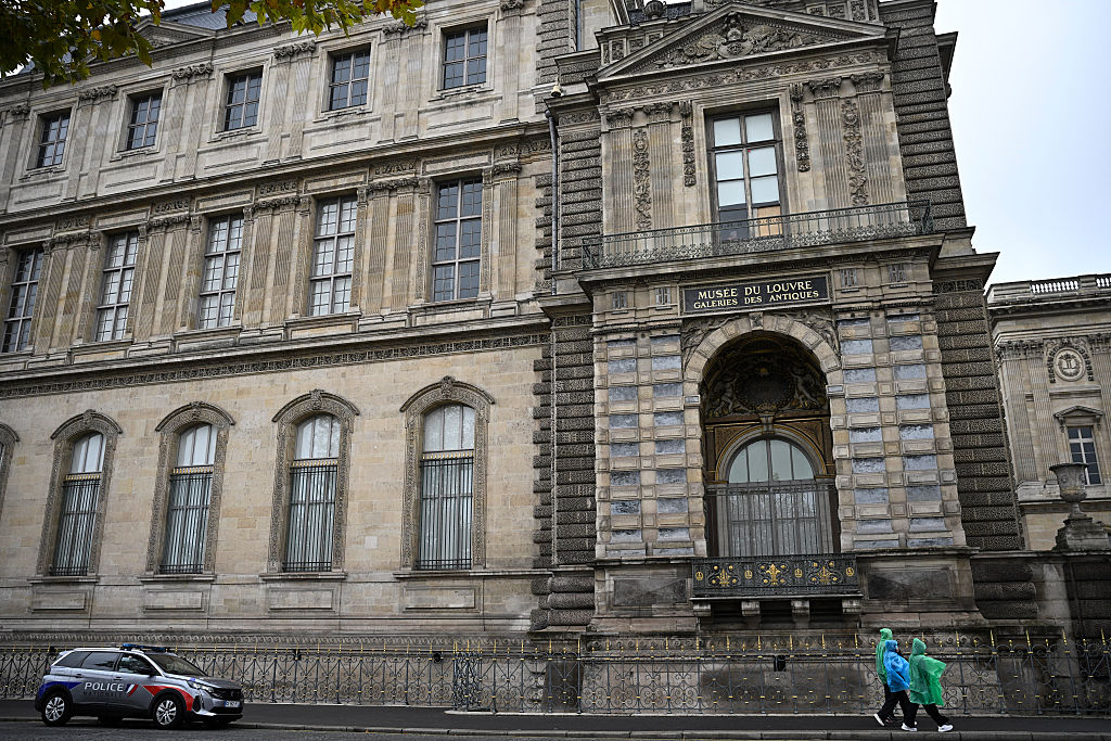 Ein Polizeiauto wird geparkt, während Menschen unter dem Fenster hindurchgehen, durch das die Diebe eingestiegen sind, die am Vortag acht unbezahlbare königliche Schmuckstücke aus dem Louvre-Museum gestohlen haben, in Paris am 20. Oktober 2025. | Quelle: Getty Images