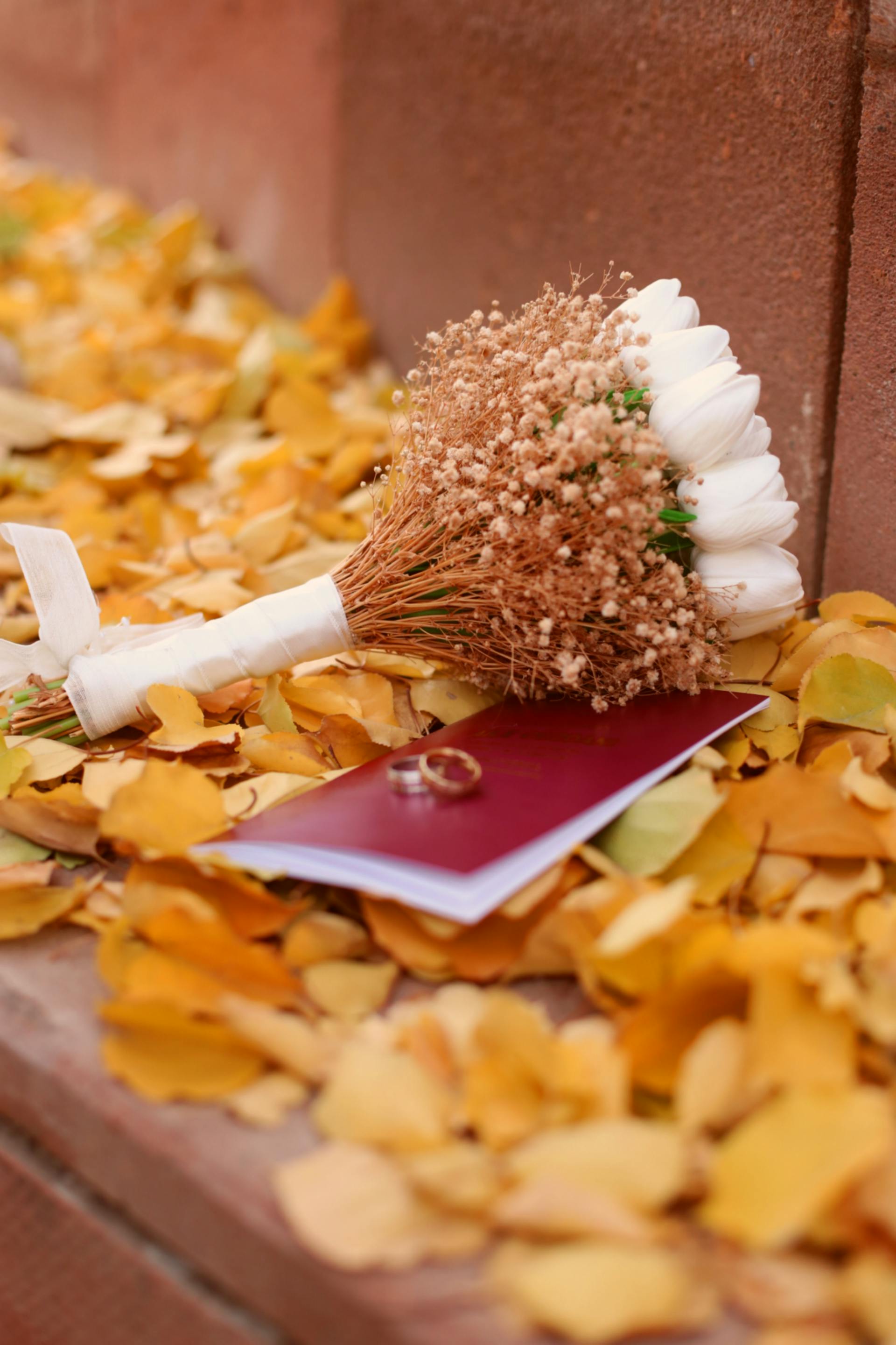 Ein Hochzeitsstrauß mit Ringen, die auf Herbstblättern liegen | Quelle: Pexels
