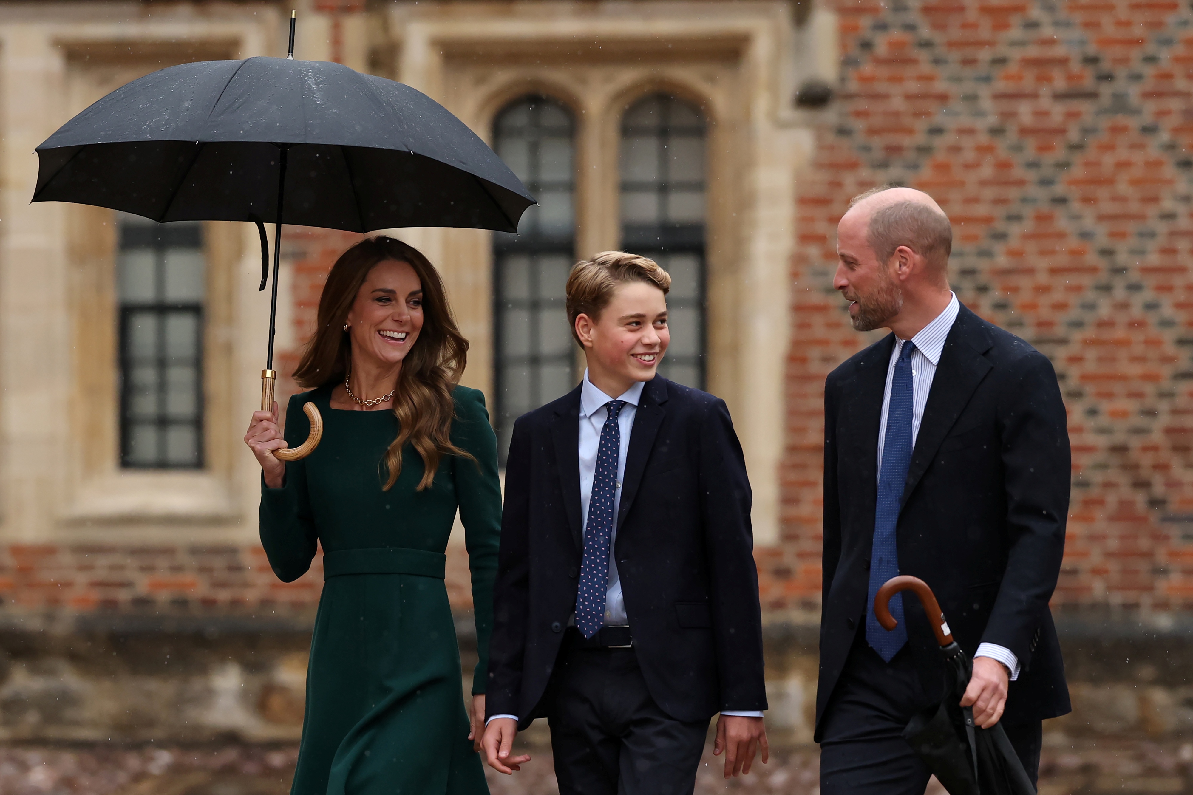 George wandte sich in einem unbeschwerten Moment zu William um, während Catherine unter einem Regenschirm neben ihnen herging. Das Familienfoto hielt fest, wie die Eltern ihren ältesten Sohn in seine nächste Bildungsphase begleiteten.