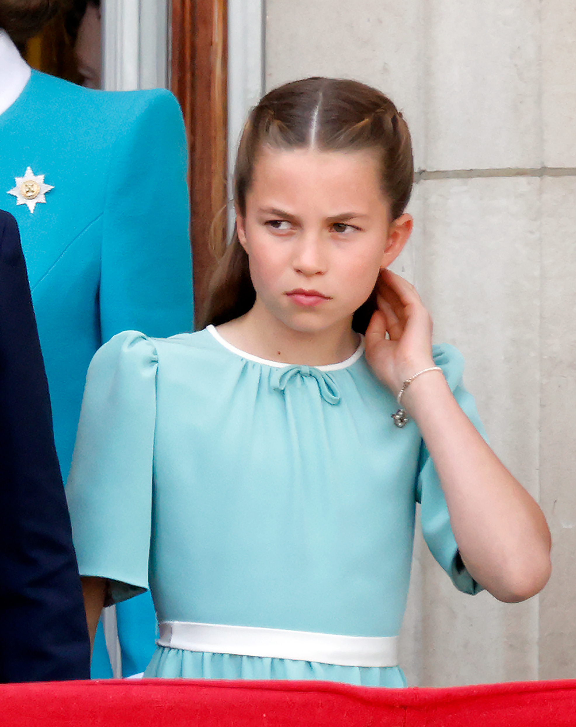Prinzessin Charlotte von Wales, in ihrem wunderschönen weißen und aquamarinfarbenen Kleid, ihrer prächtigen Frisur und ihrem Armreif, berührt ihr Haar und beobachtet einen RAF-Flugvorbeiflug vom Balkon des Buckingham Palace während des Trooping The Colour 2025 in London, England am 14. Juni 2025.
