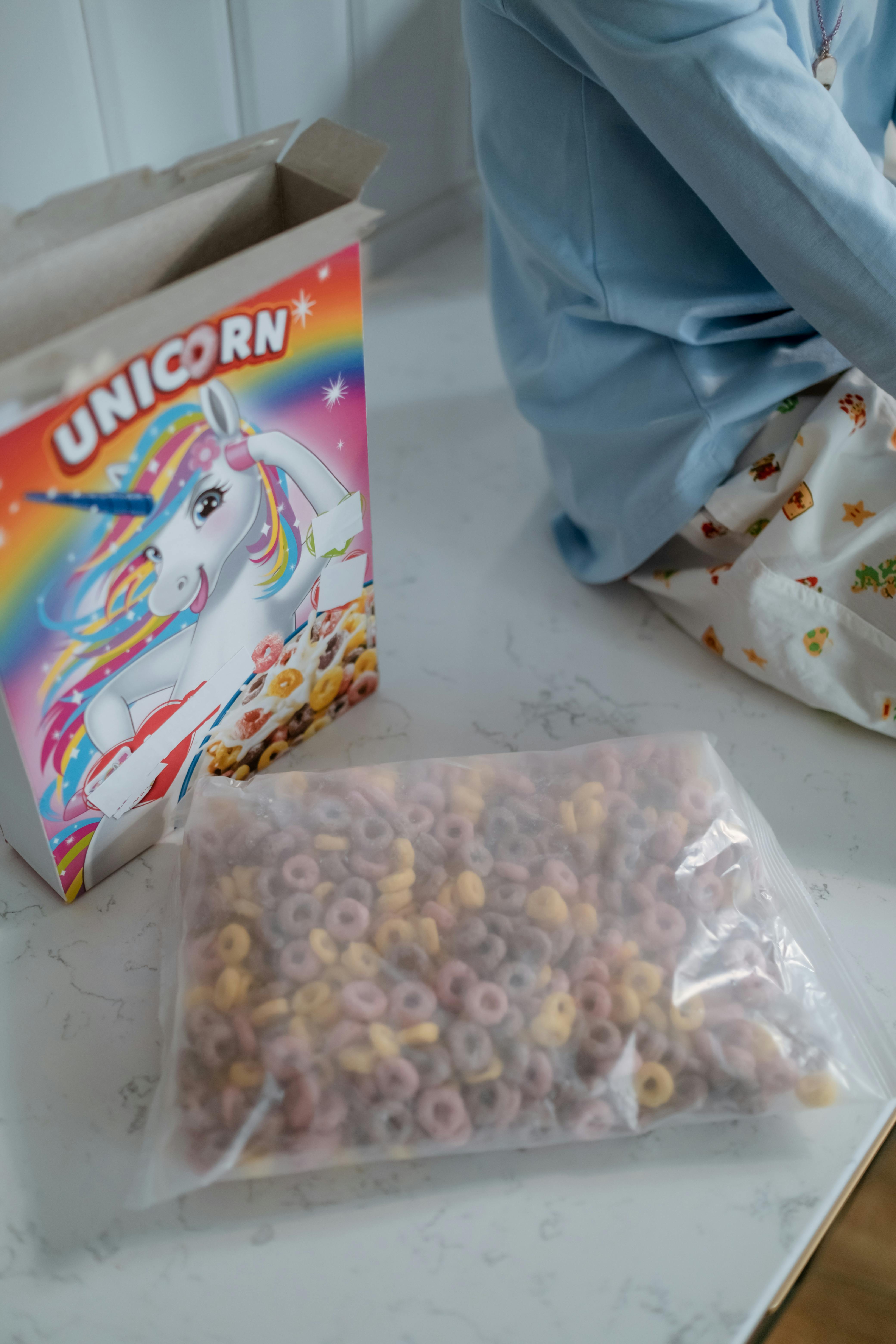 Ein Kind sitzt mit einer Tüte Müsli auf dem Küchentisch | Quelle: Pexels