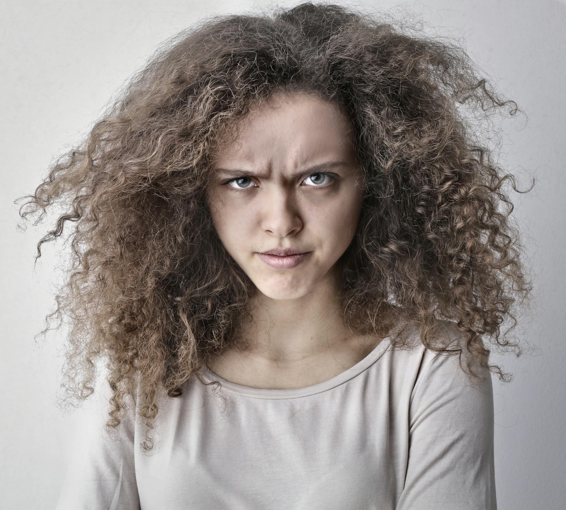 Eine junge Frau mit lockigem Haar, die ihre Augenbrauen runzelt | Quelle: Pexels