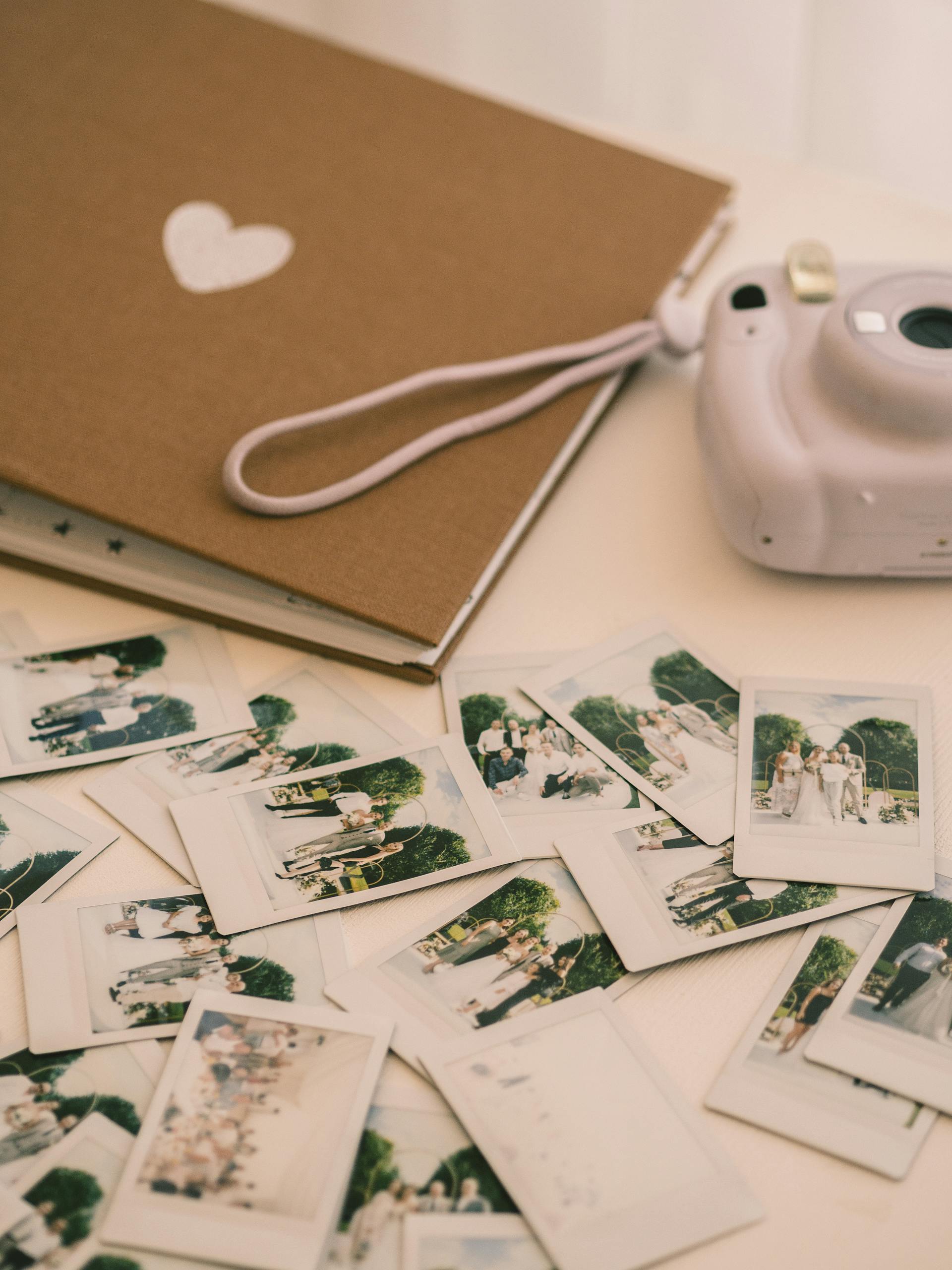 Eine Kamera, ein Fotoalbum und Bilder liegen auf einer weißen Fläche | Quelle: Pexels