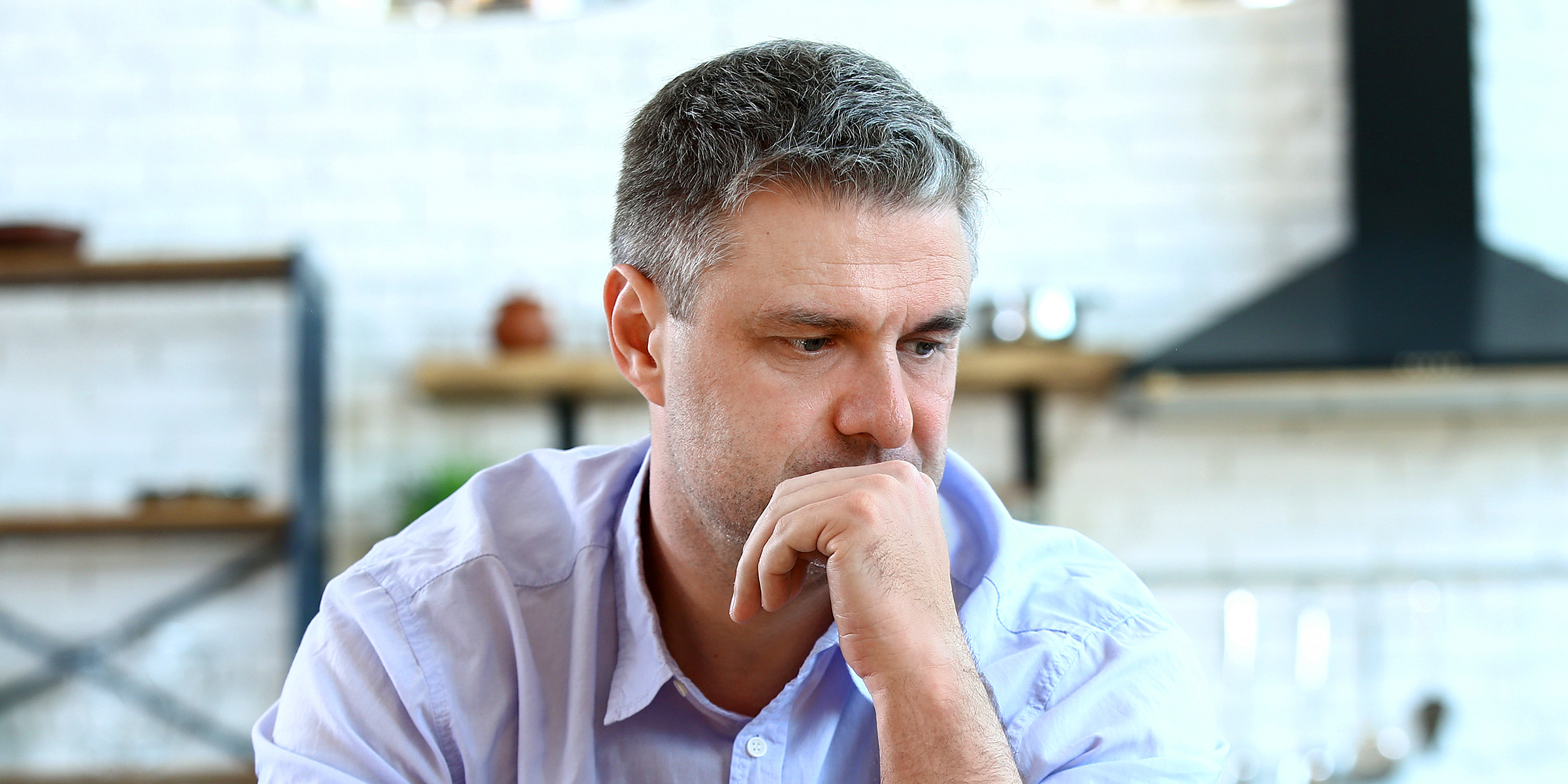 Ein nachdenklicher Mann sitzt an einem Tisch | Quelle: Shutterstock