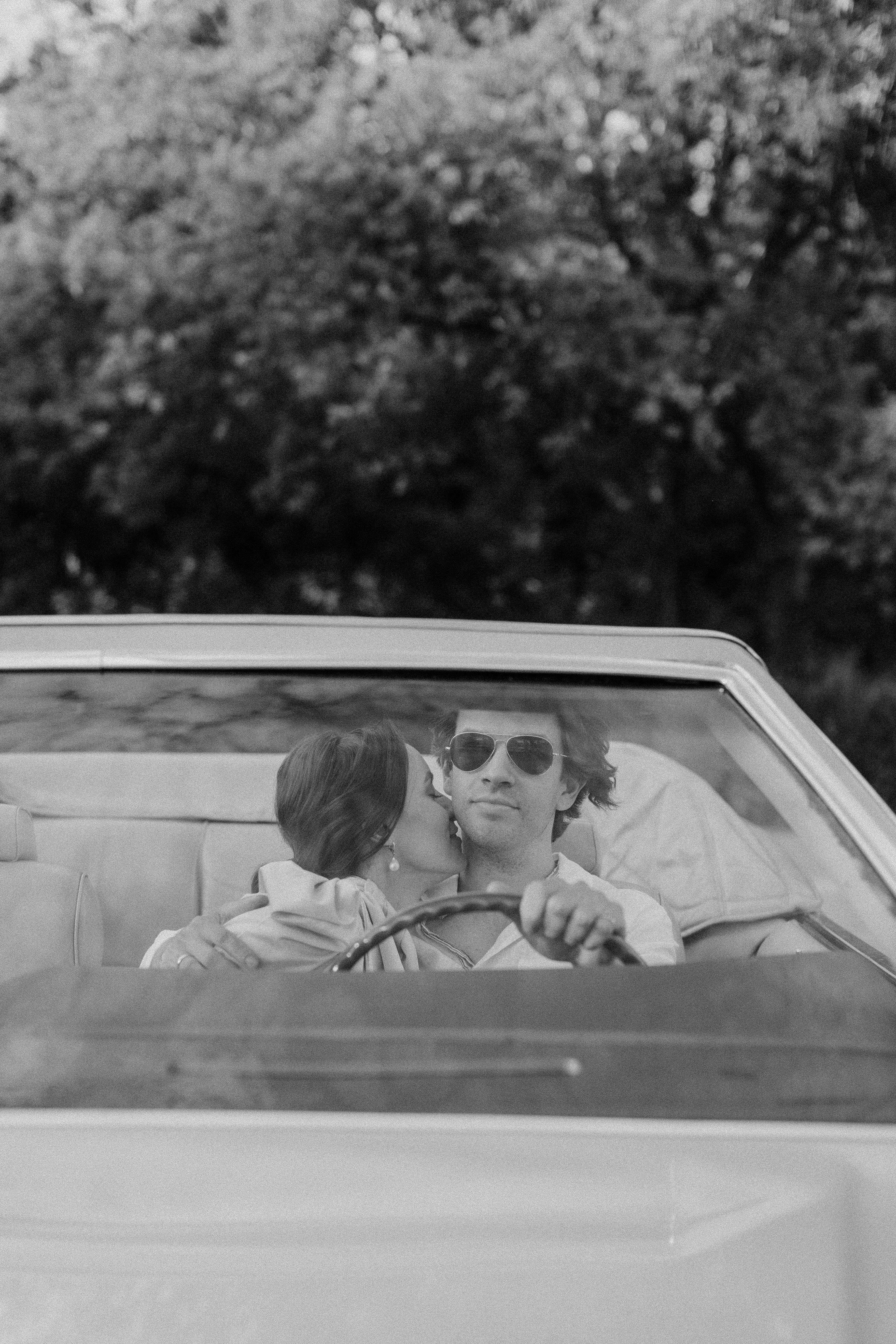 Ein Mann fährt, während eine Frau ihn küsst | Quelle: Pexels